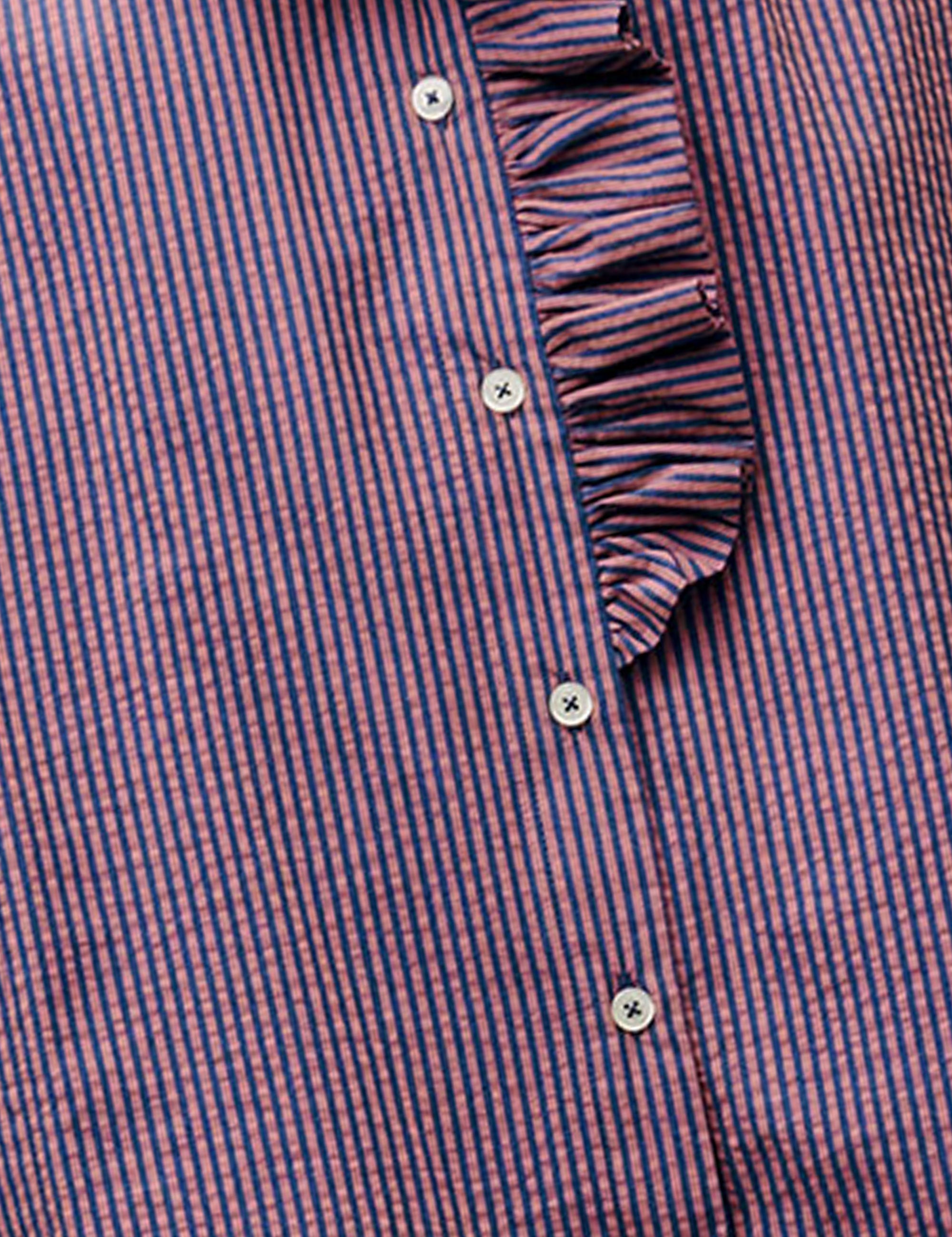 Close-up of a purple and white striped shirt with ruffled trim.