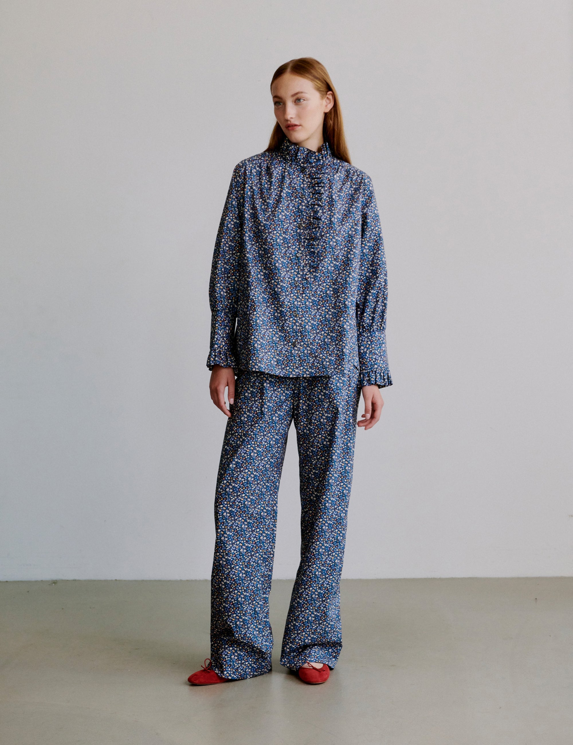 Woman wearing a blue floral patterned outfit with long sleeve frilled shirt and pants