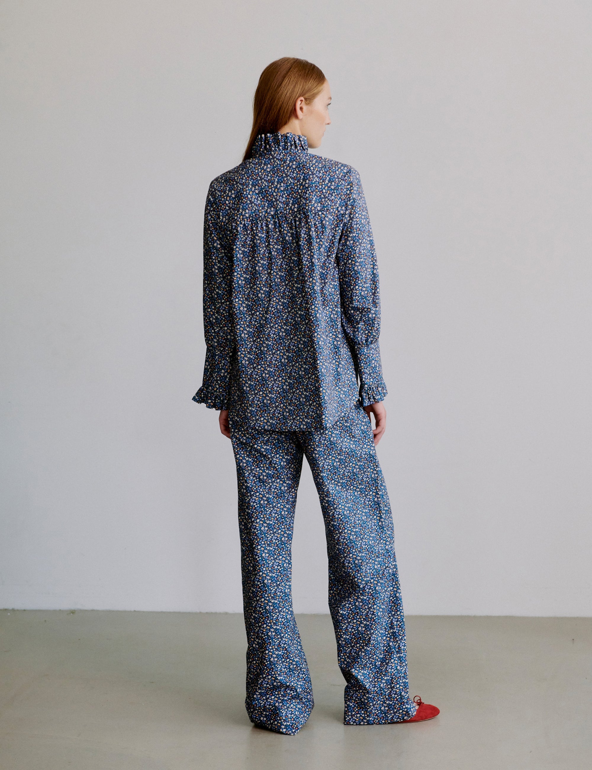 Woman wearing a blue floral patterned outfit with long sleeve frilled shirt and pants
