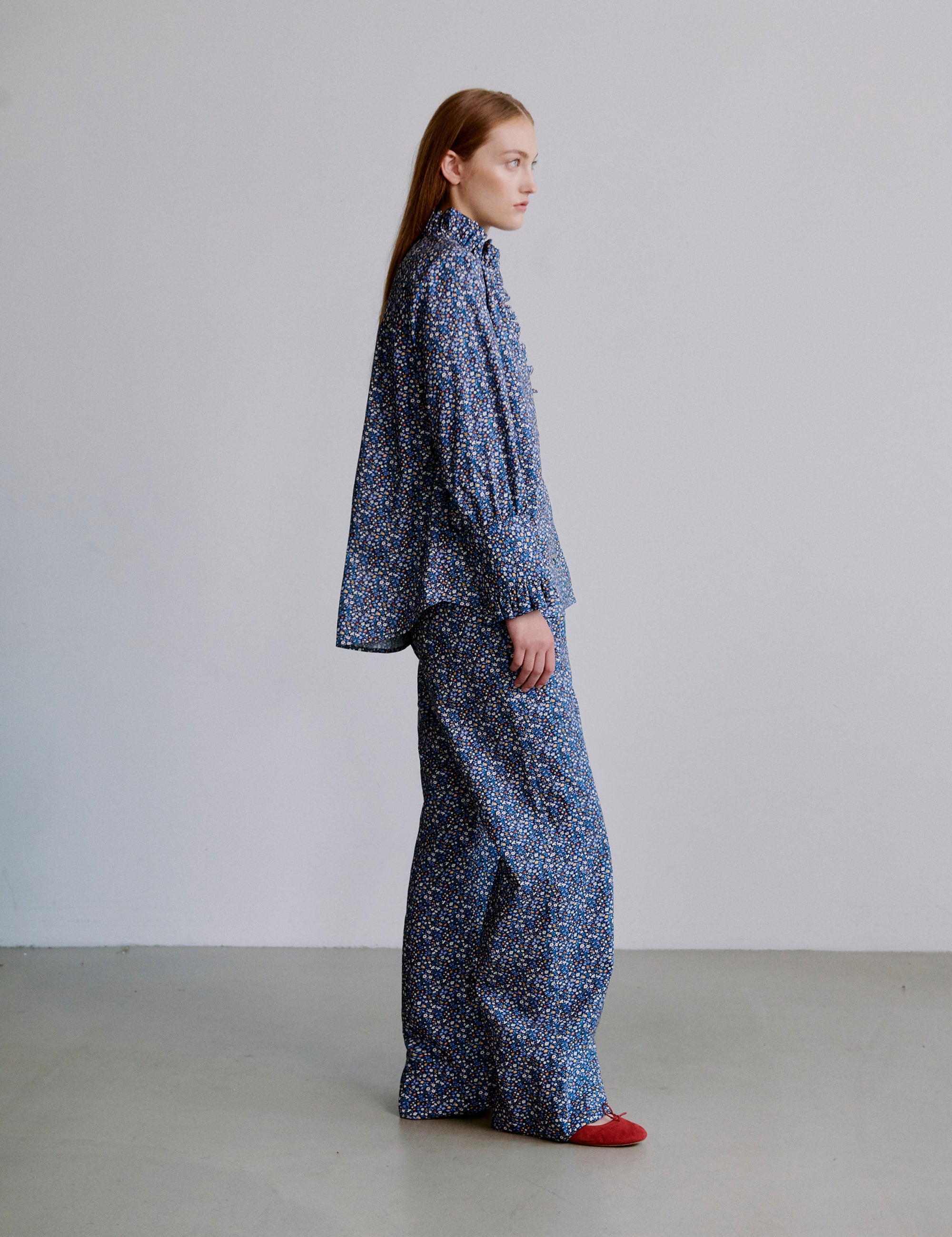 Woman wearing a blue floral patterned outfit with long sleeve frilled shirt and pants