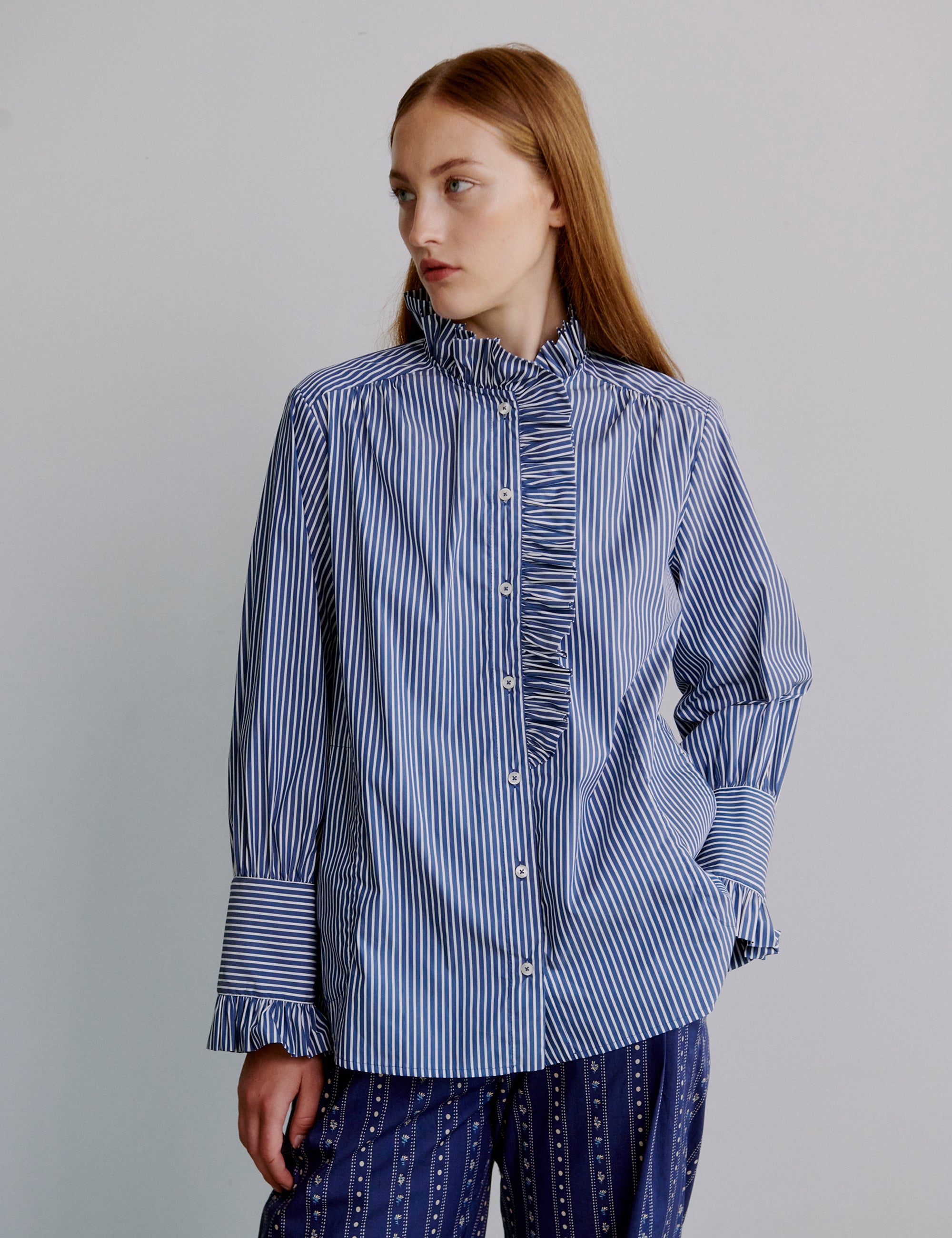 Woman wearing a blue and white striped shirt with frilled collar and cuffs
