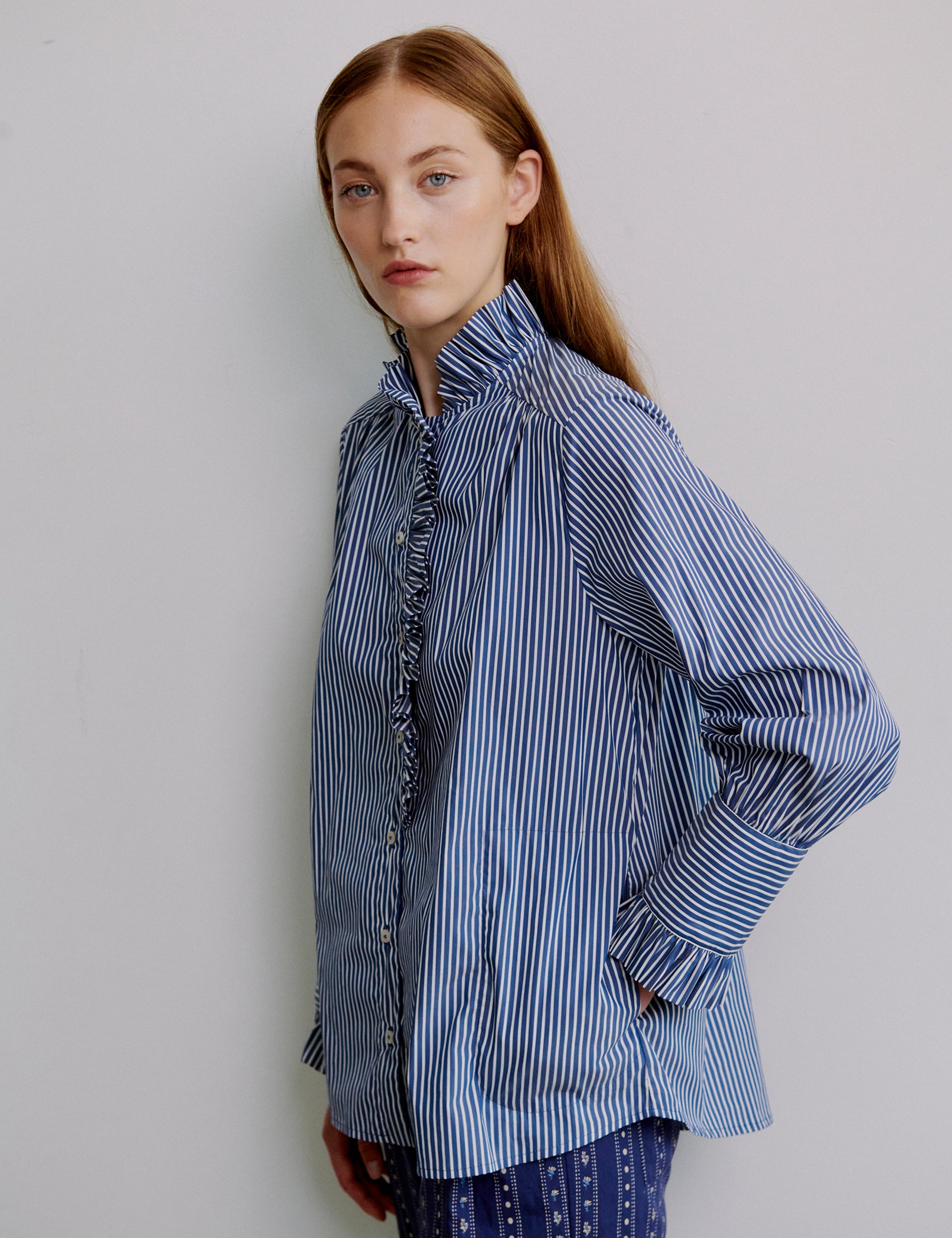 Woman wearing a blue and white striped shirt with frilled collar and cuffs