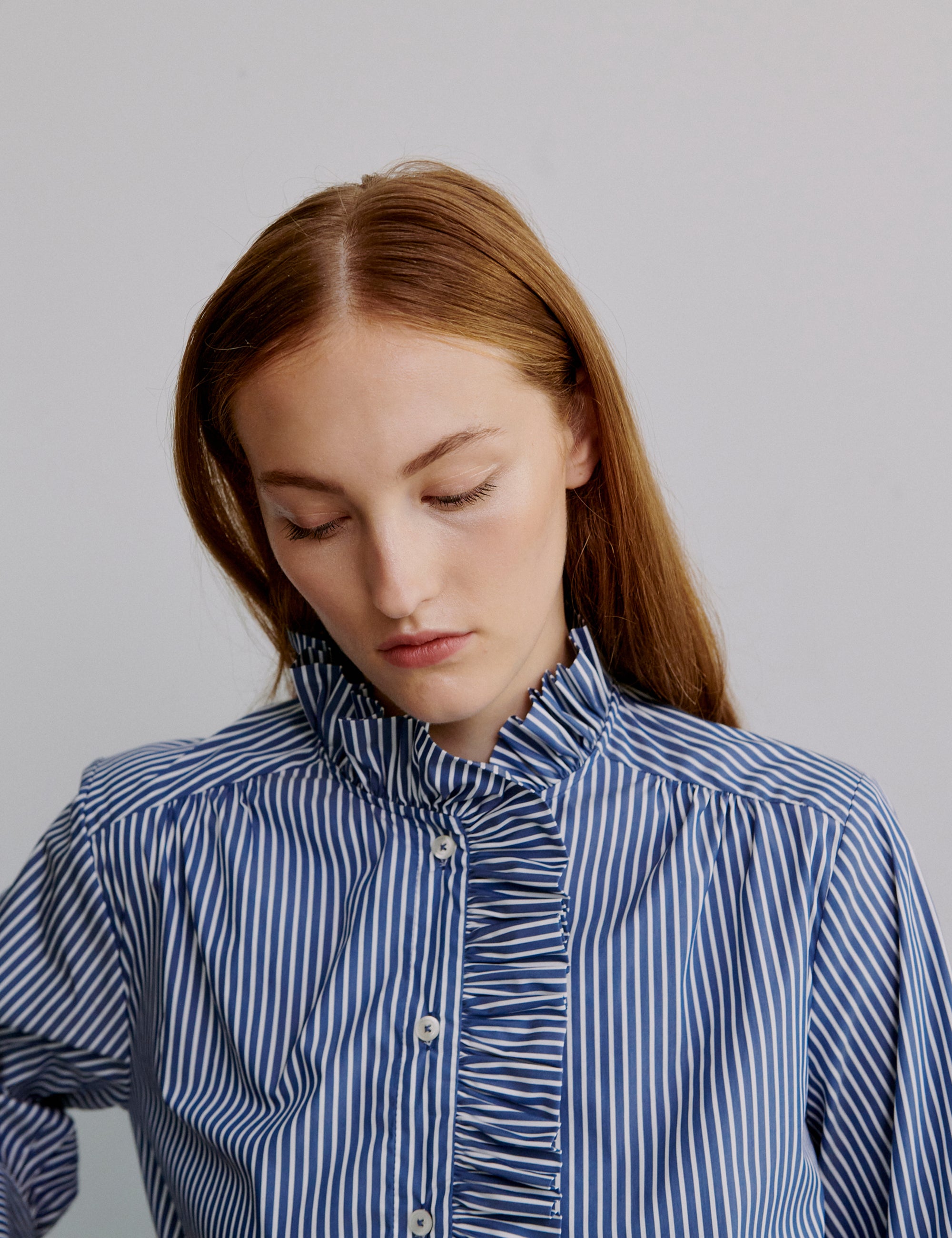 Woman wearing a blue and white striped shirt with frilled collar