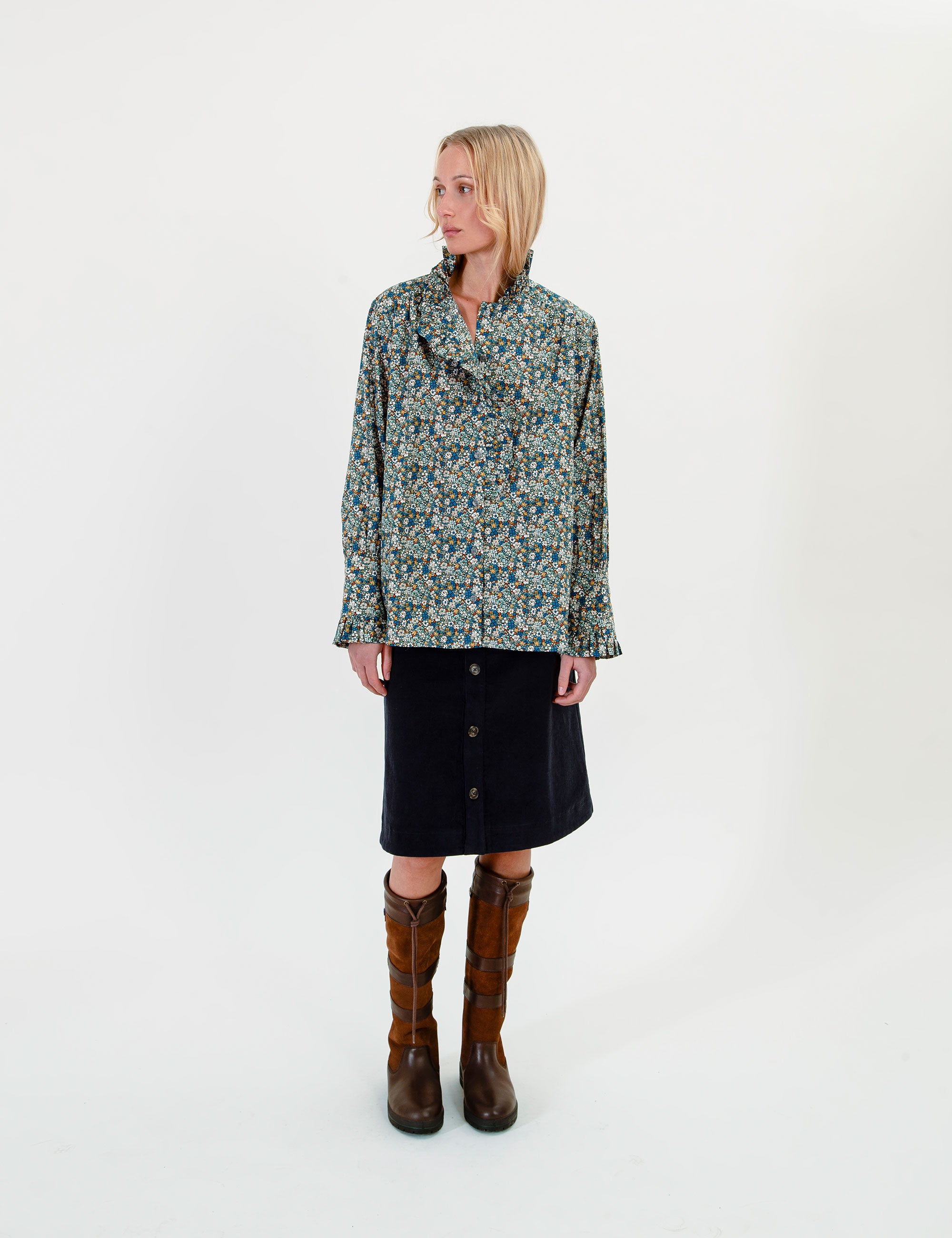 Woman wearing a floral blouse with frills and a knee-lpng dark blue skirt