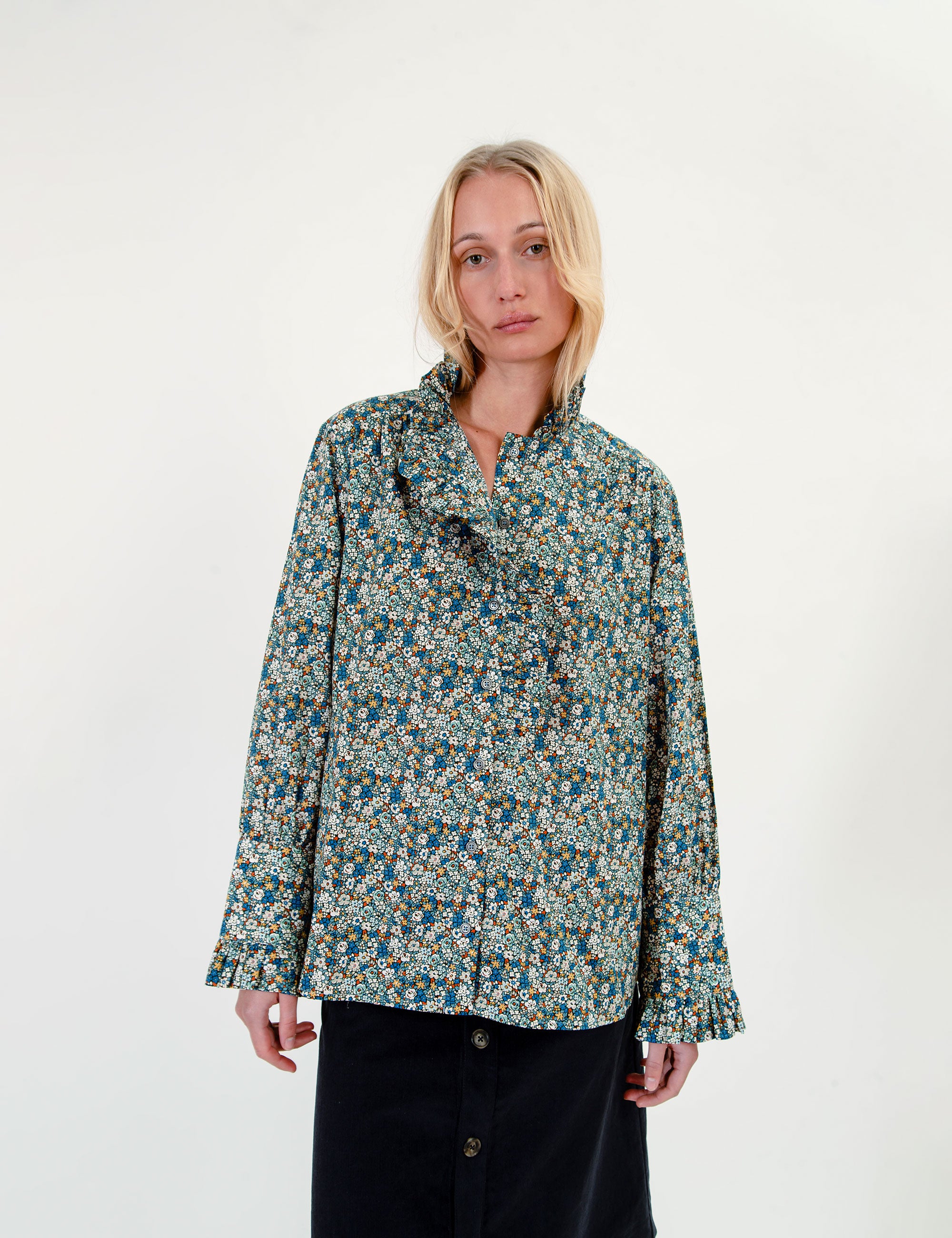 Woman wearing a floral blouse with frills and a knee-lpng dark blue skirt