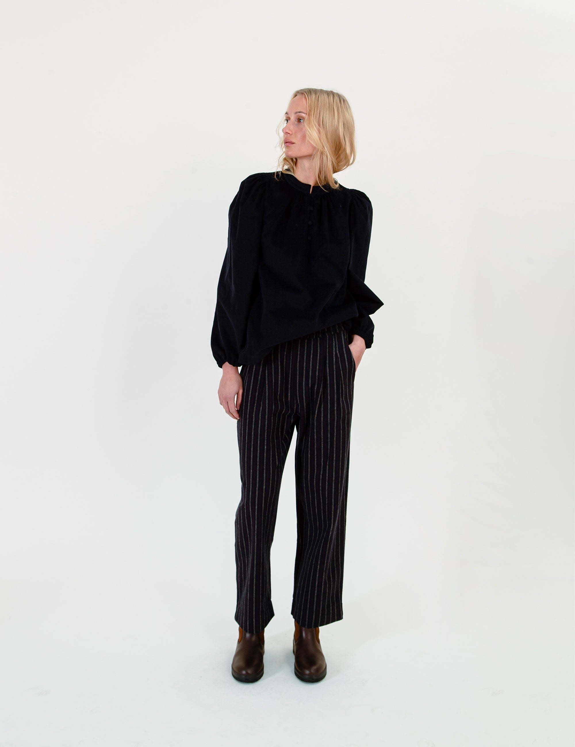 Woman wearing a black sweater and striped pants on a white background