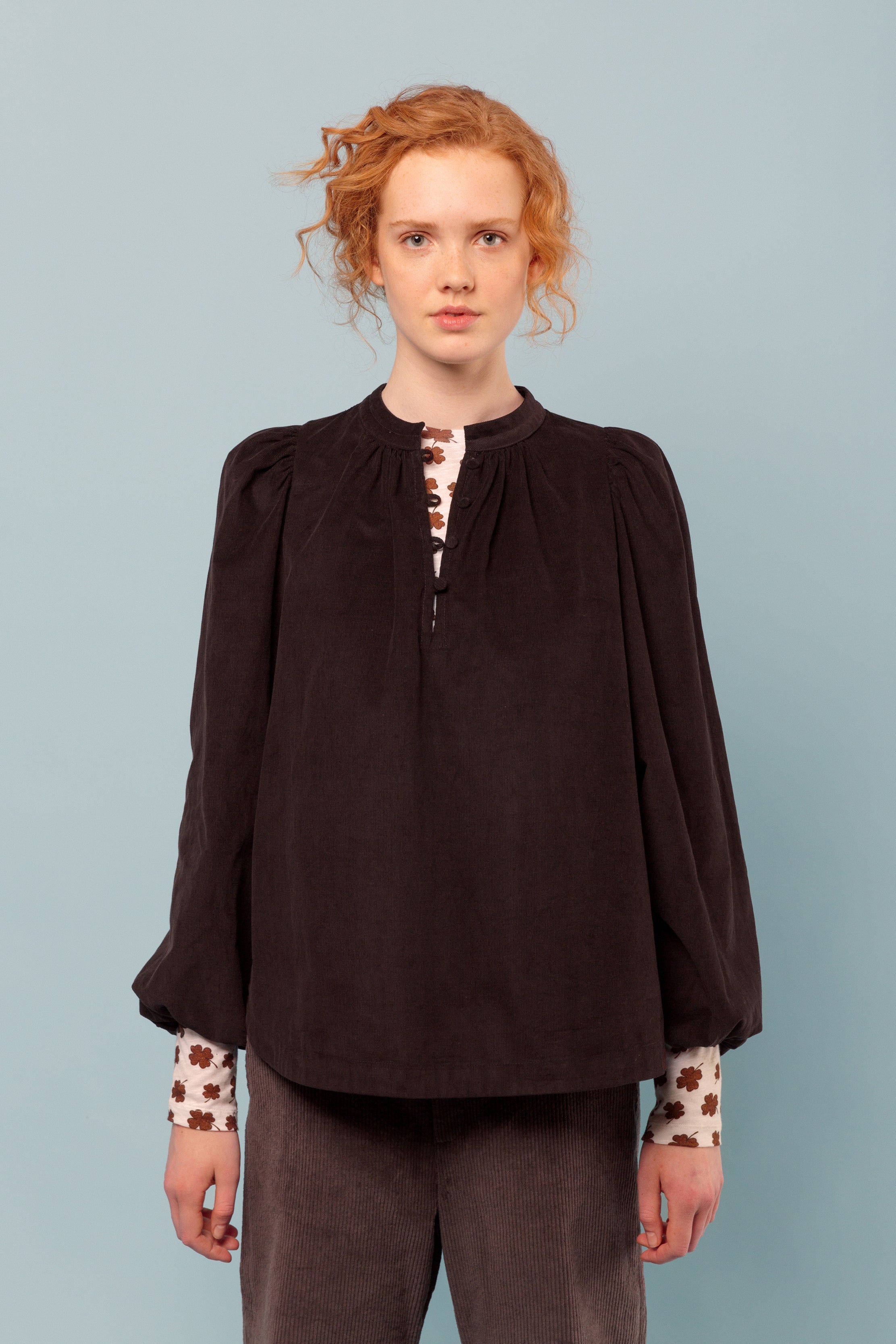 Woman in brown corduroy shirt and t-shirt with lucky clover print