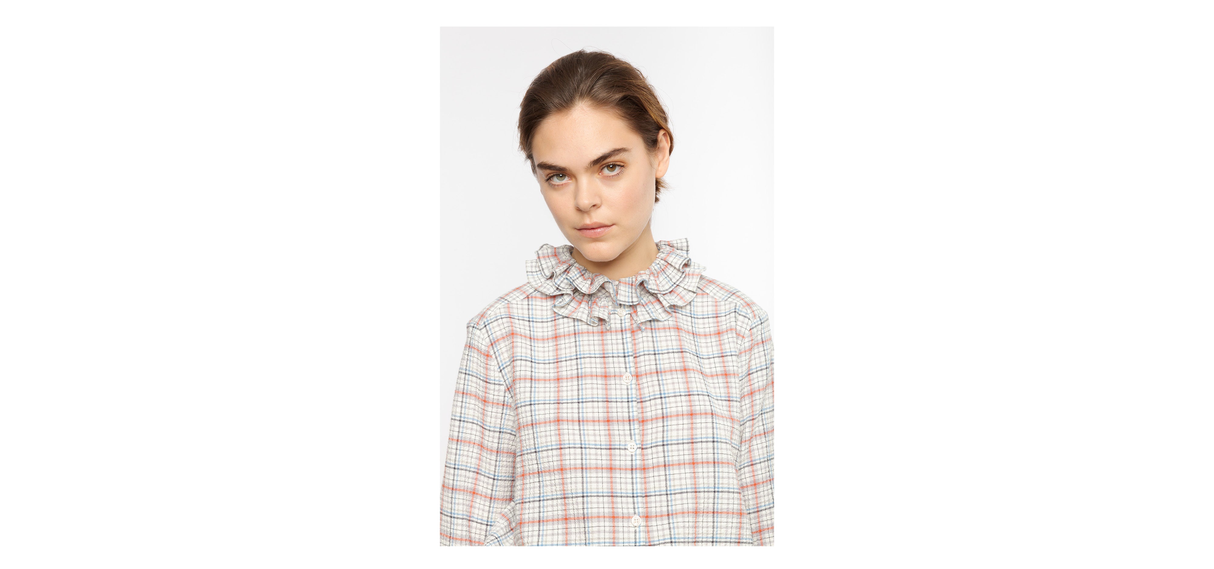 Woman in multi-colored shirt with check pattern and frilled collar