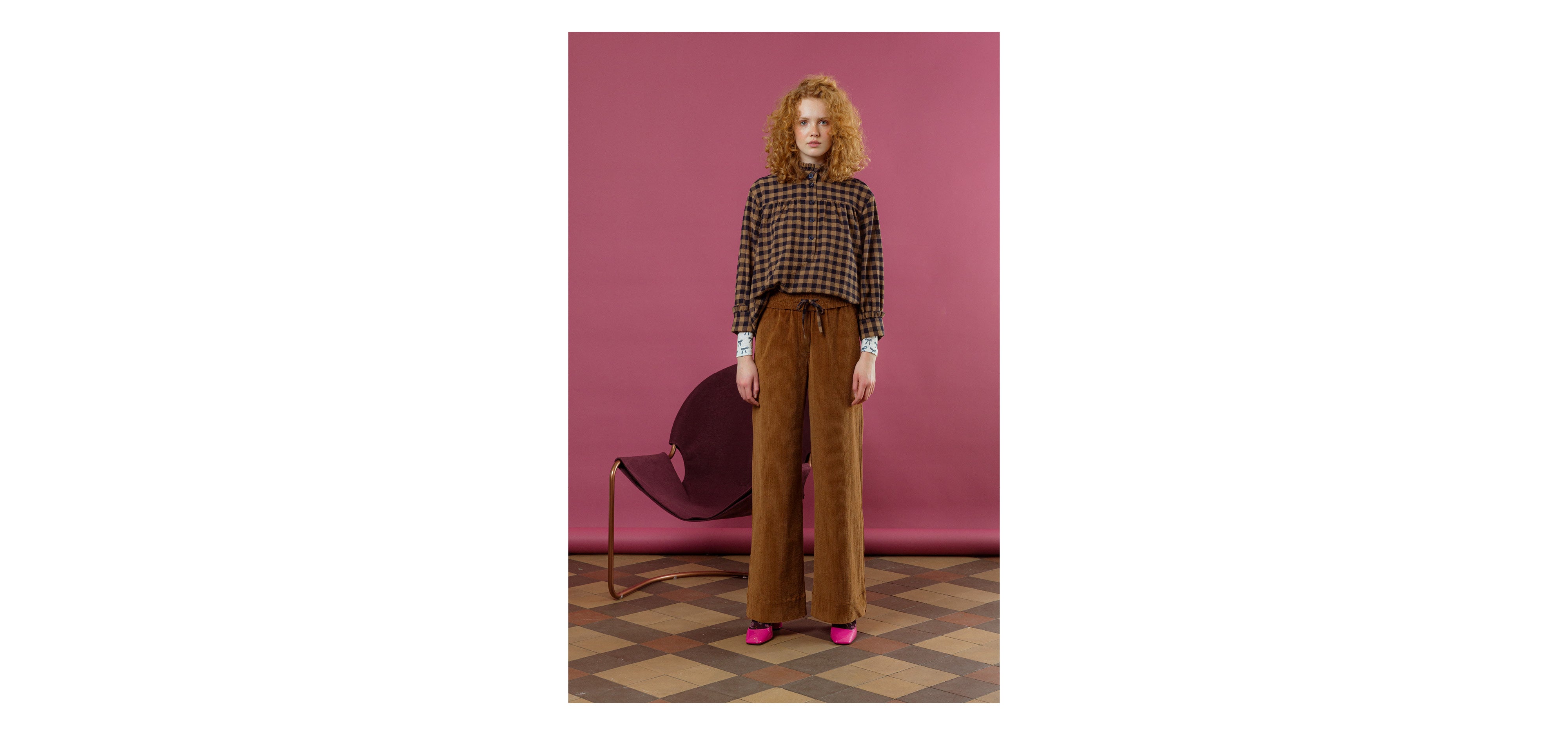 Woman in brown pants and long sleeved shirt with black and brown check pattern