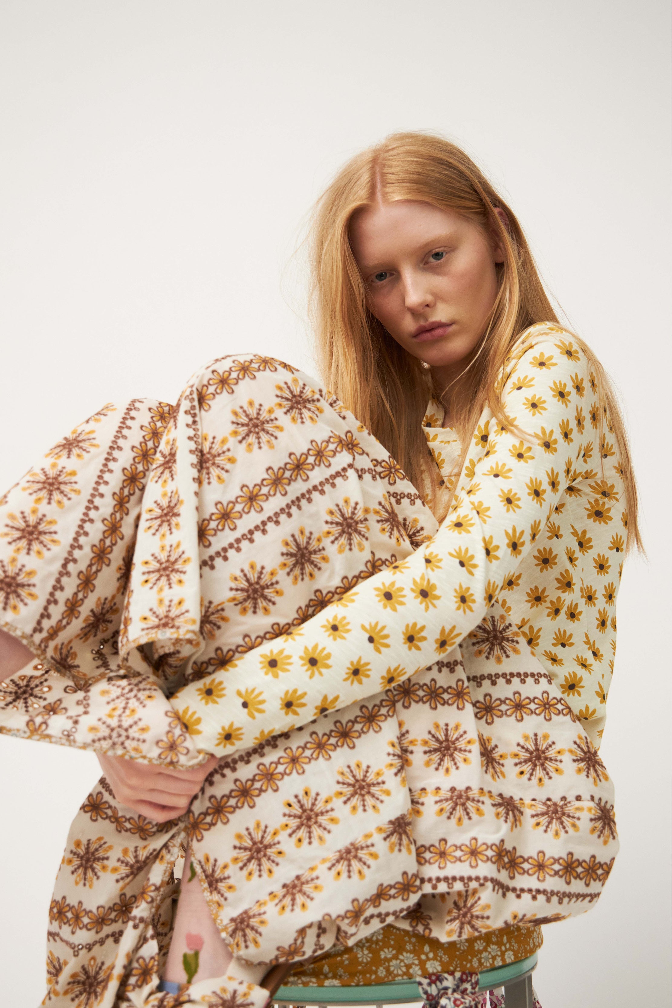 Kvinna i långärmad t-shirt med solrosmönster och spetsmönstrad maxikjol