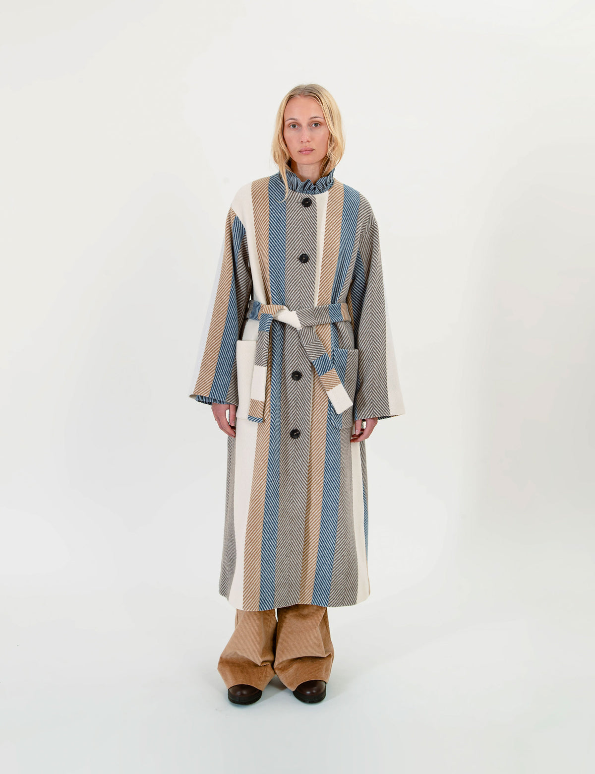 Woman wearing a long, striped wool coat with a belt on a white background