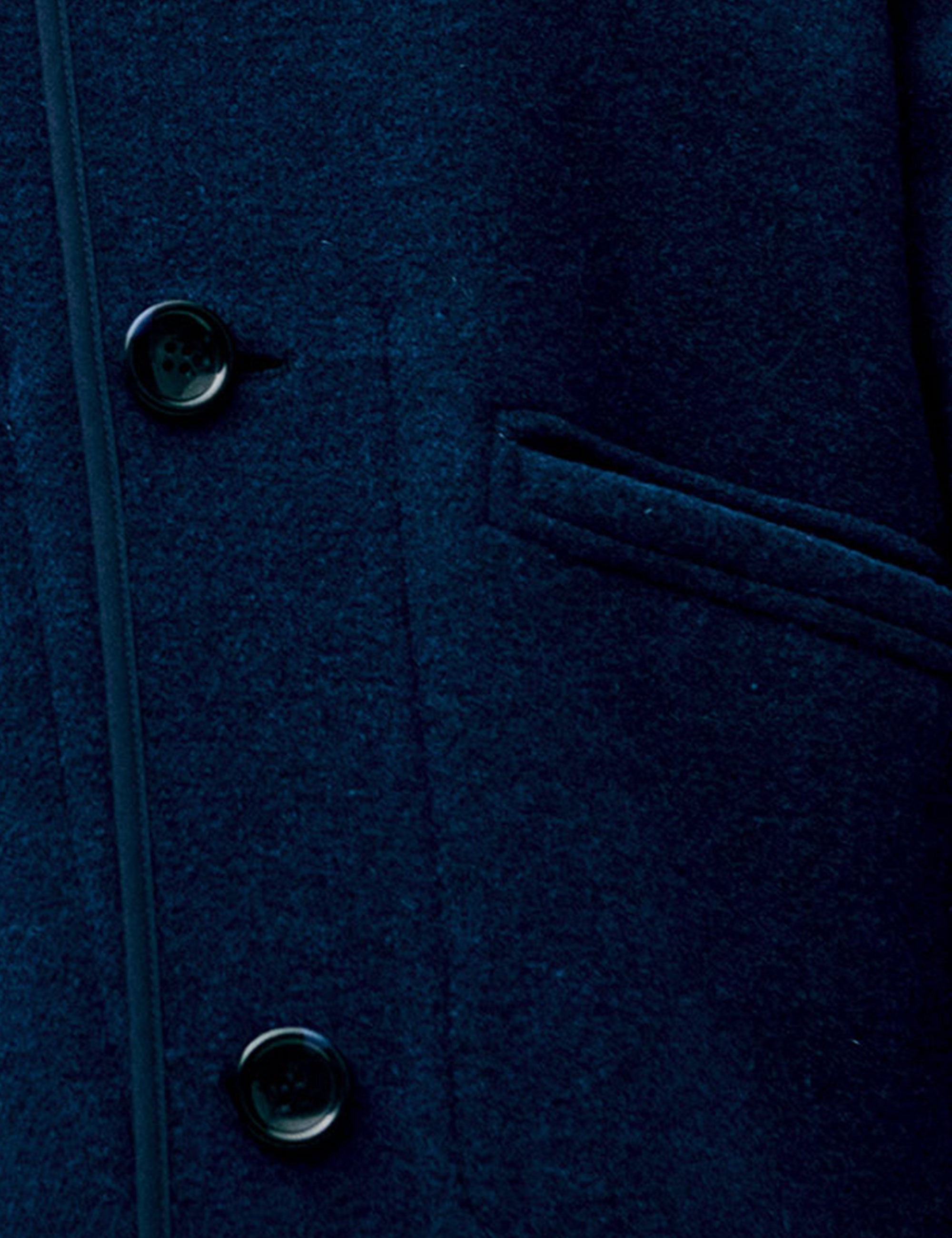 Close-up of a dark blue coat with buttons and a pocket.