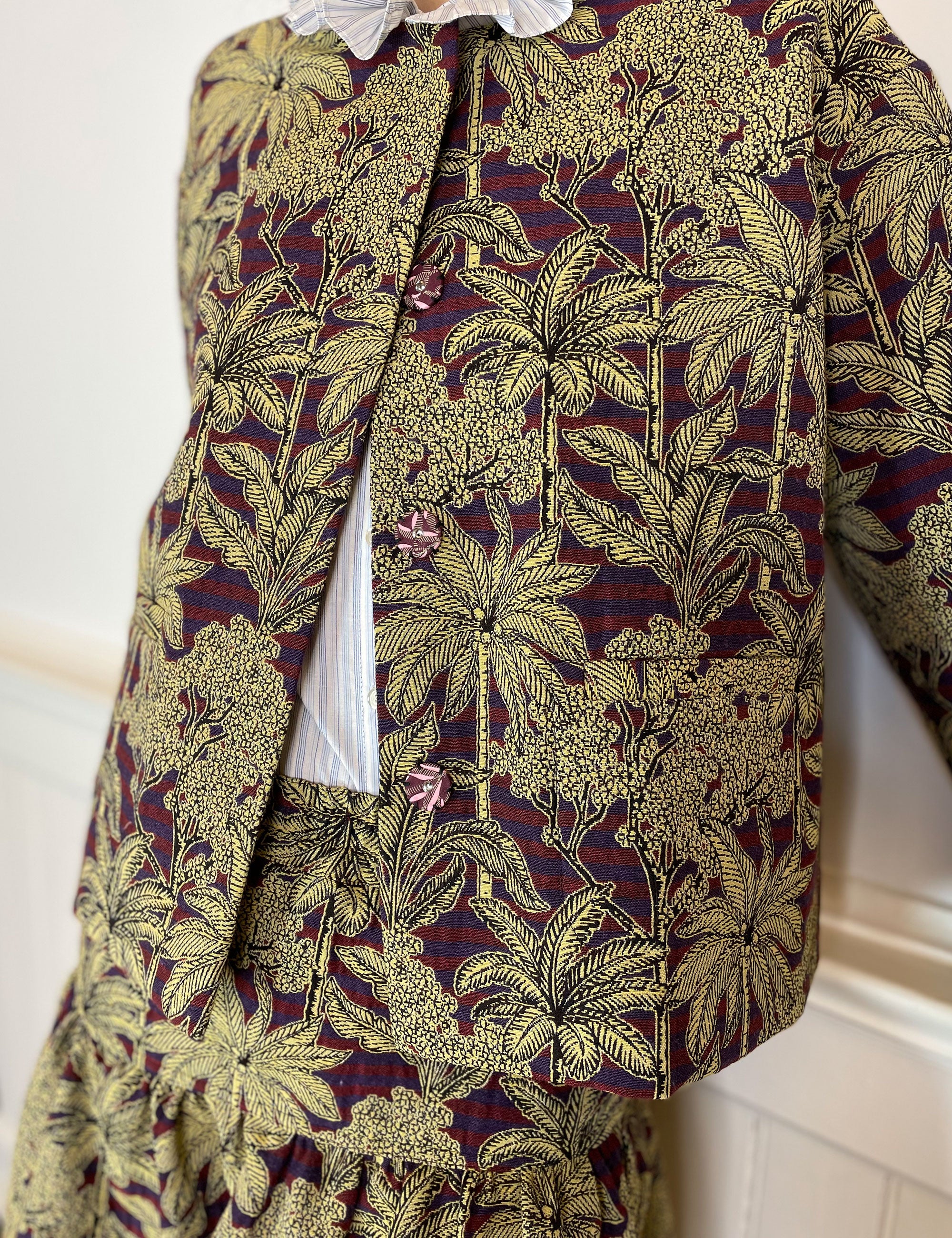 Woman in jacquard jacket and skirt with red and blue stripes and golden palm print