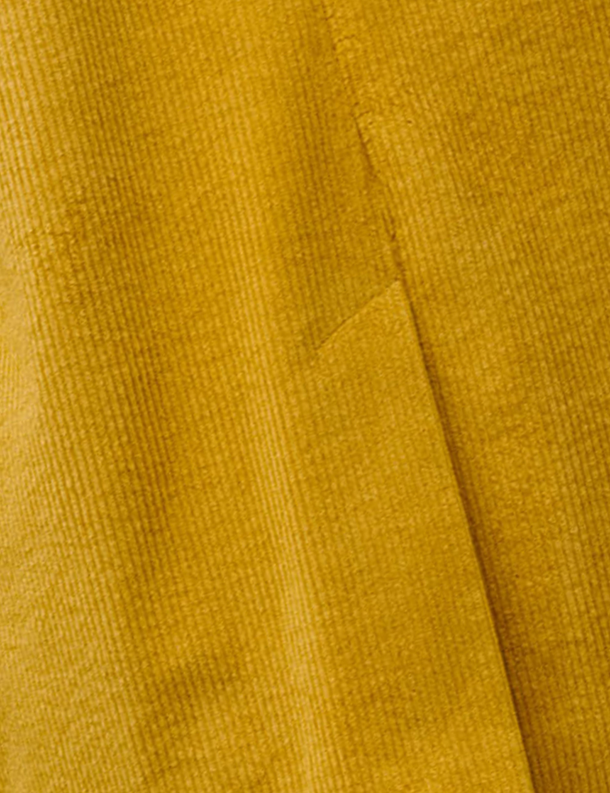 Close-up of mustard yellow corduroy fabric with visible texture and seam detail