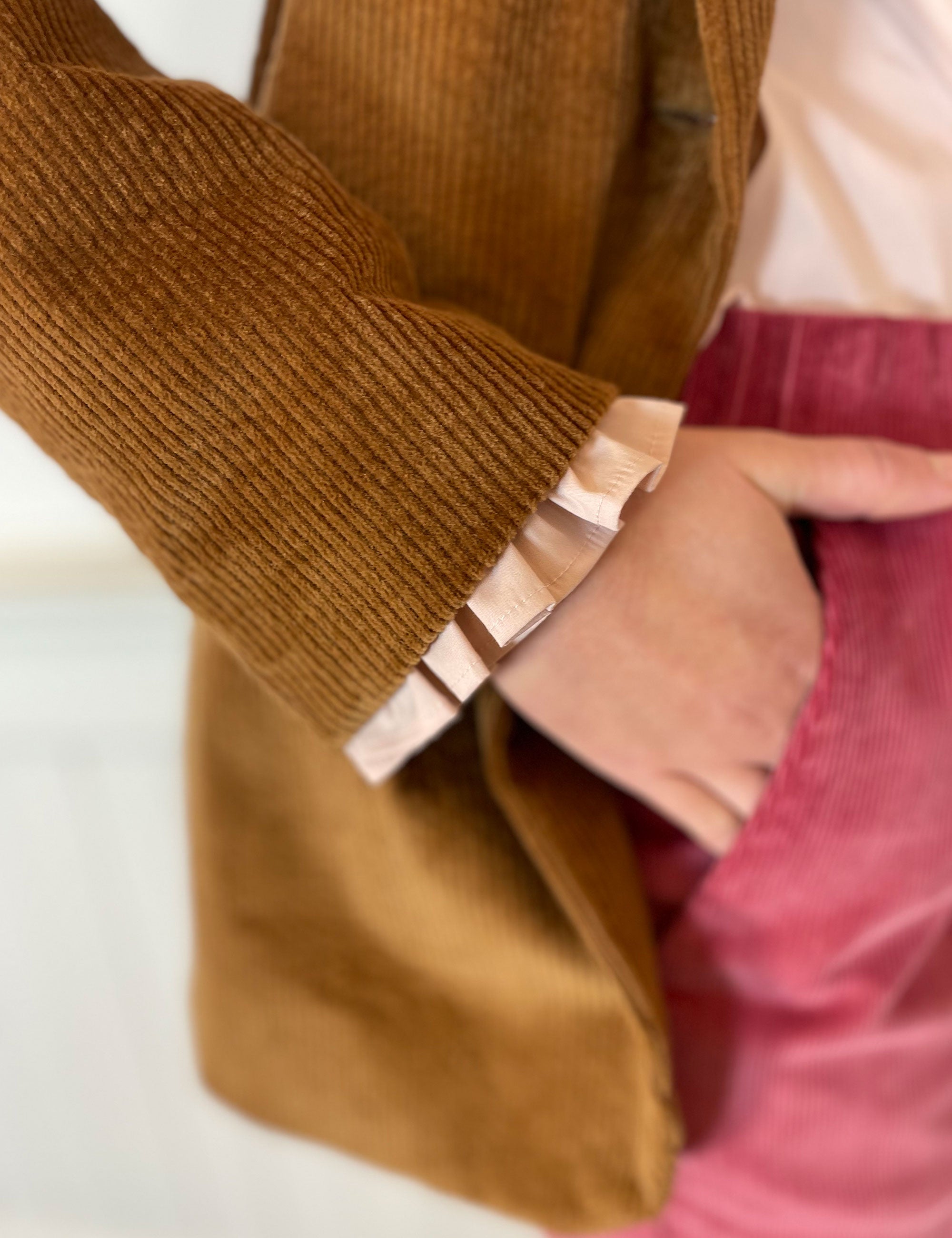 Women's dusty rose pants, pink shirt with frilled cuffs and brown corduroy jacket