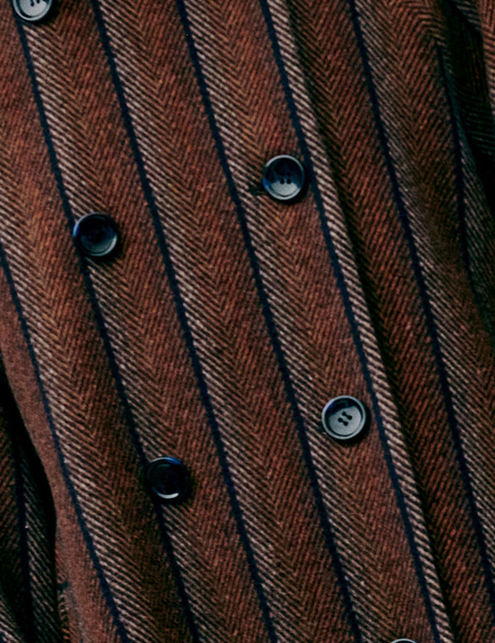 Close-up of a brown and black herringbone striped women's jacket with buttons