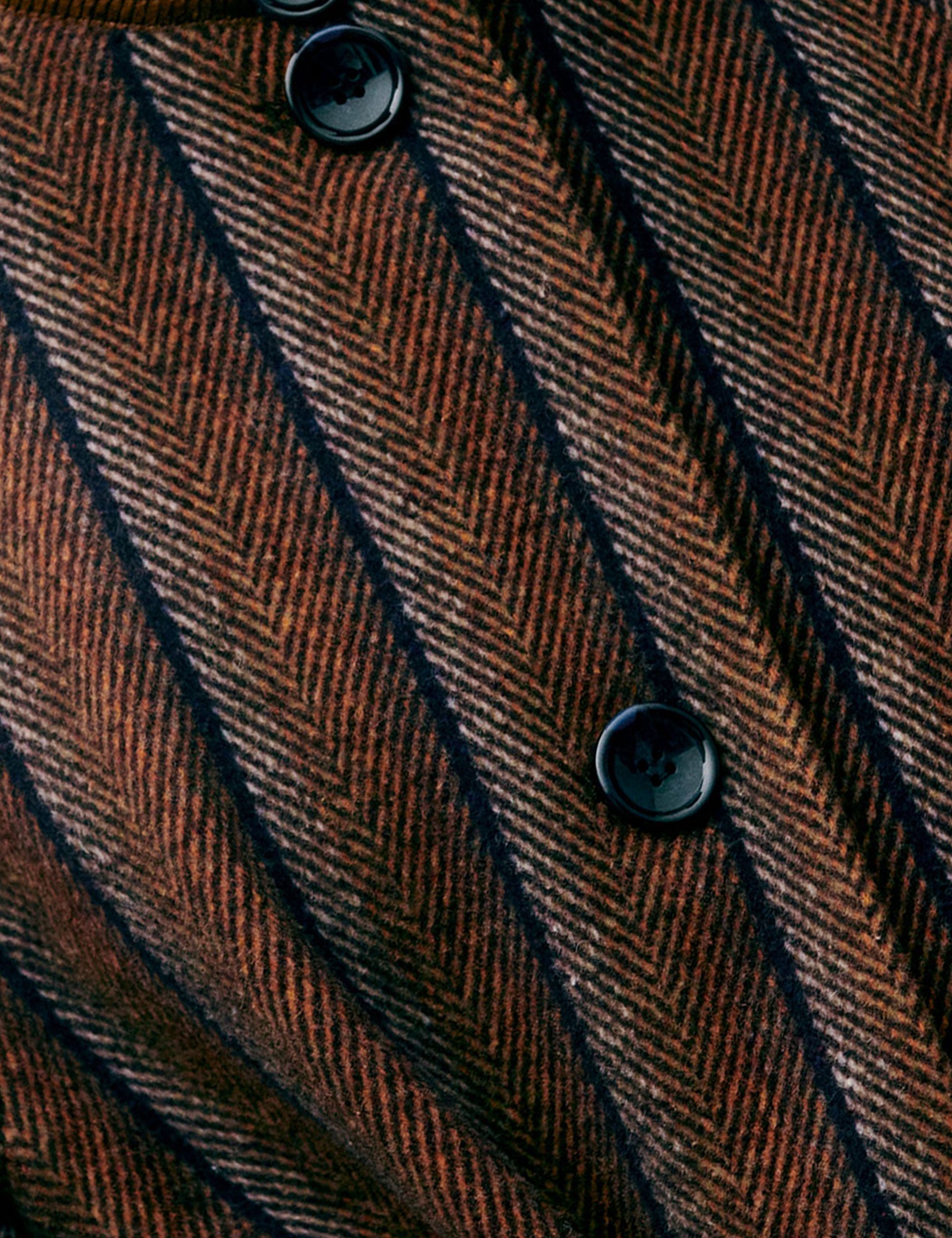 Close-up of a brown and black herringbone patterned fabric with buttons.
