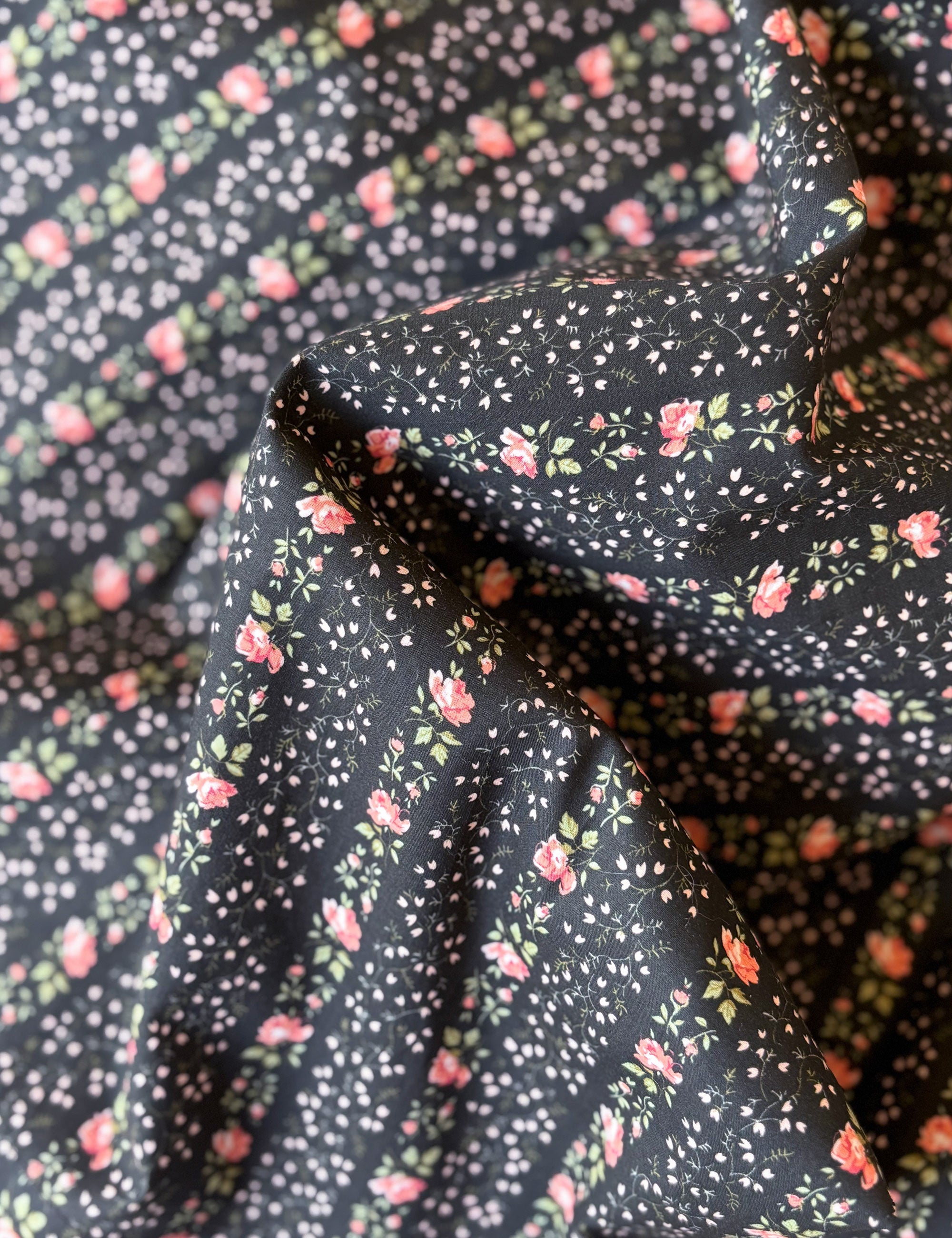 Floral fabric with small pink flowers on a dark background