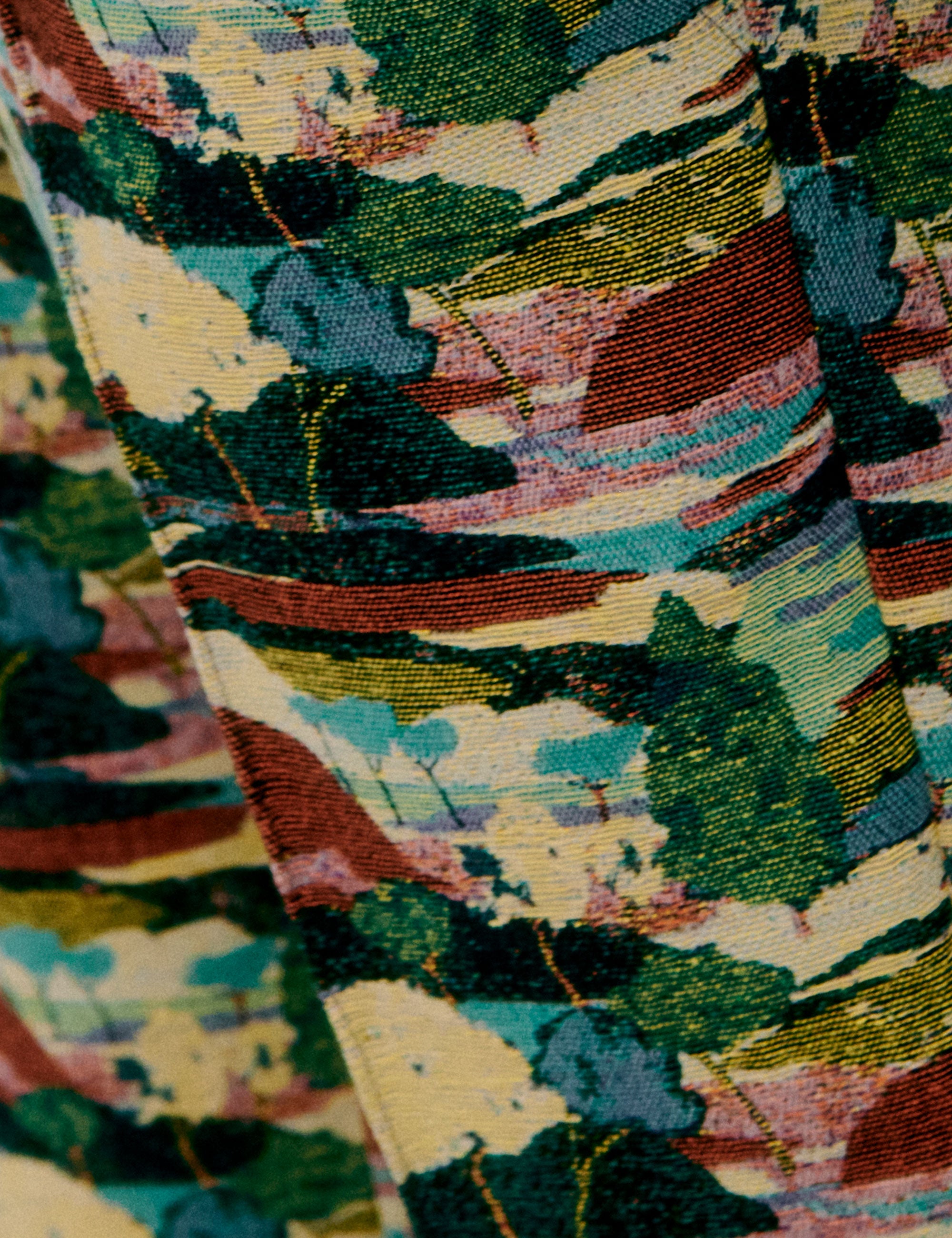 Close-up of fabric with layered print in green, red, cream, and blue tones