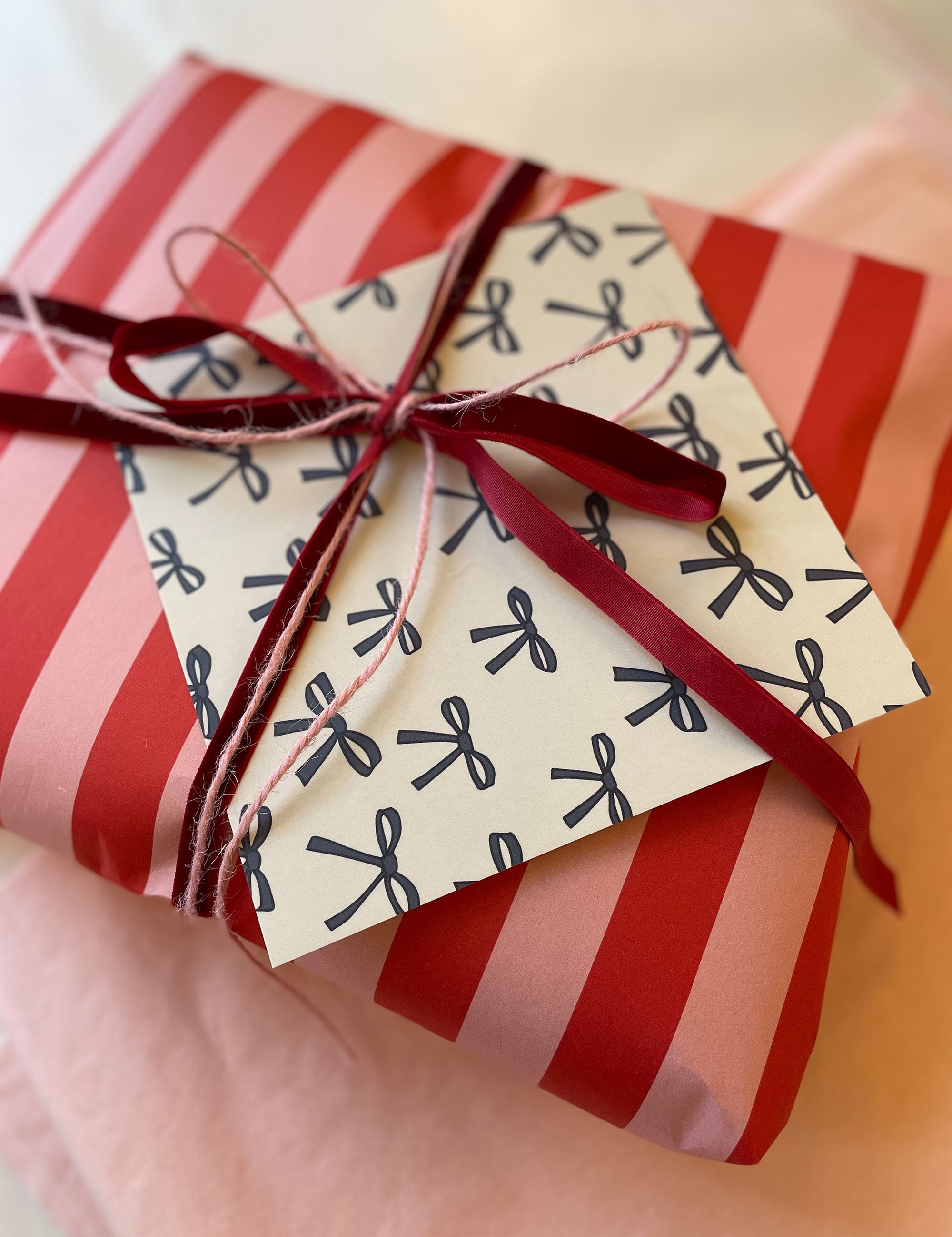 Christmas gift in red and pink wrapping, red ribbon and greeting card with blue bows