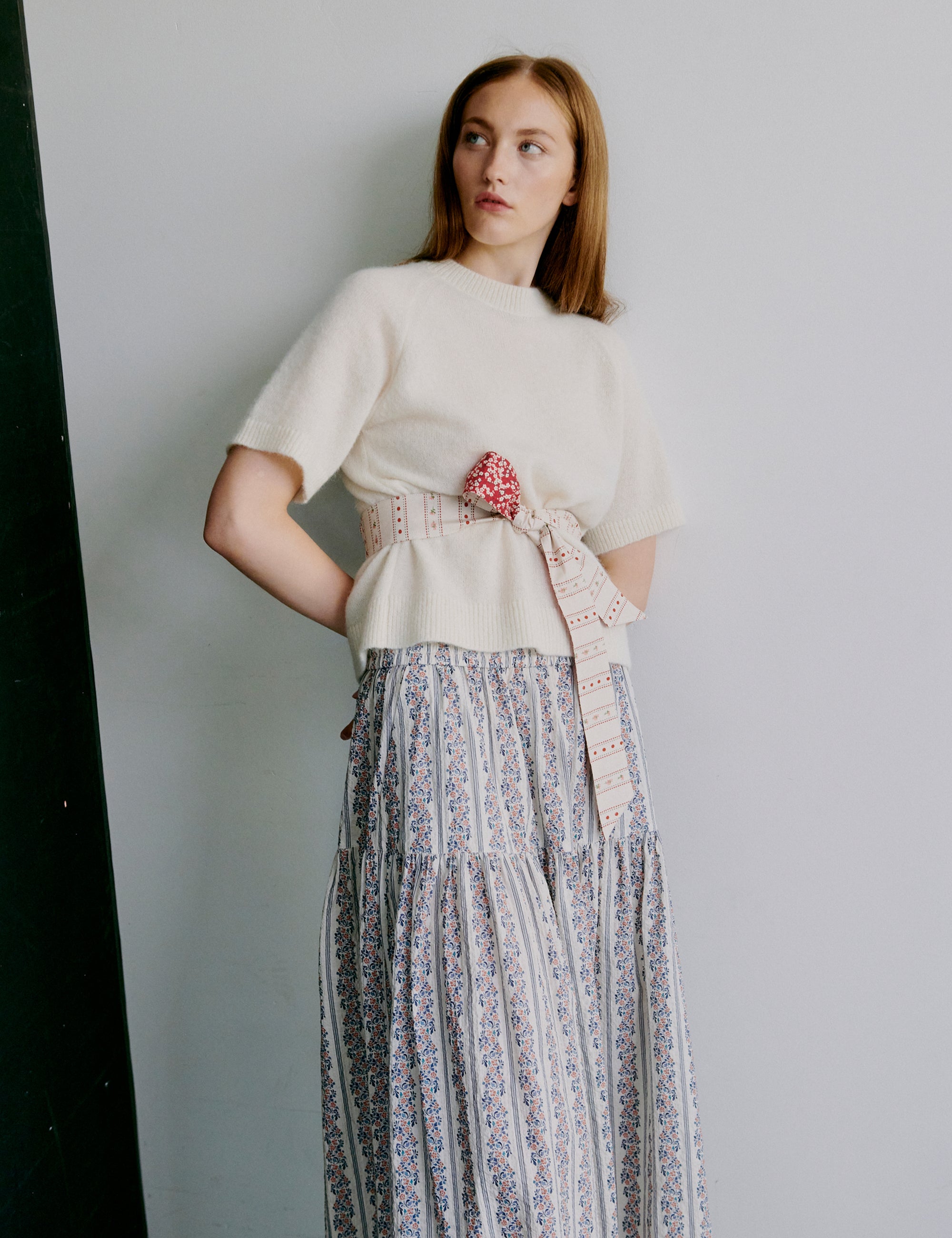 Woman wearing a white top, floral patterned skirt and floral patterned fabric belt