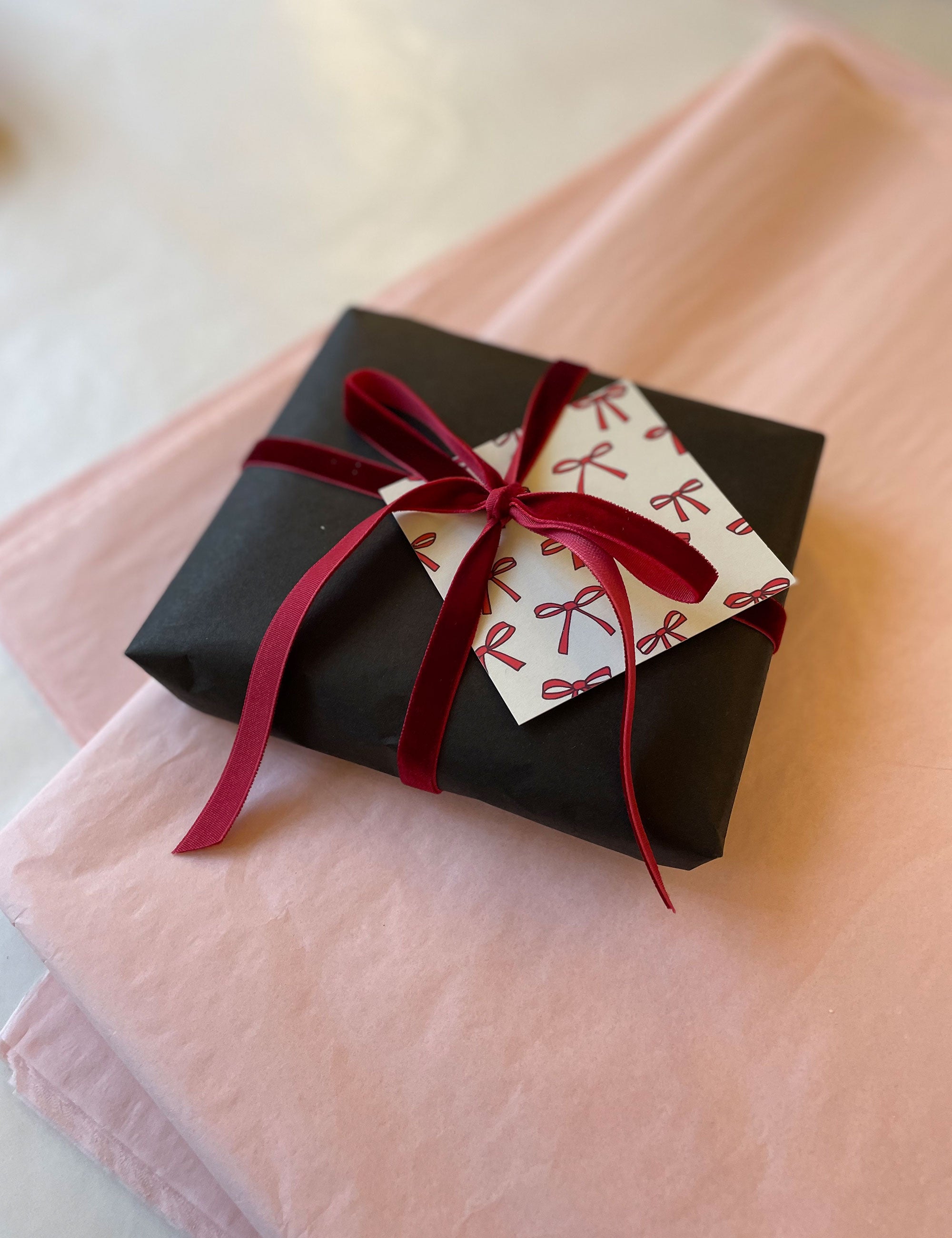 gift with black wrapping and red velvet ribbon on pink silk paper