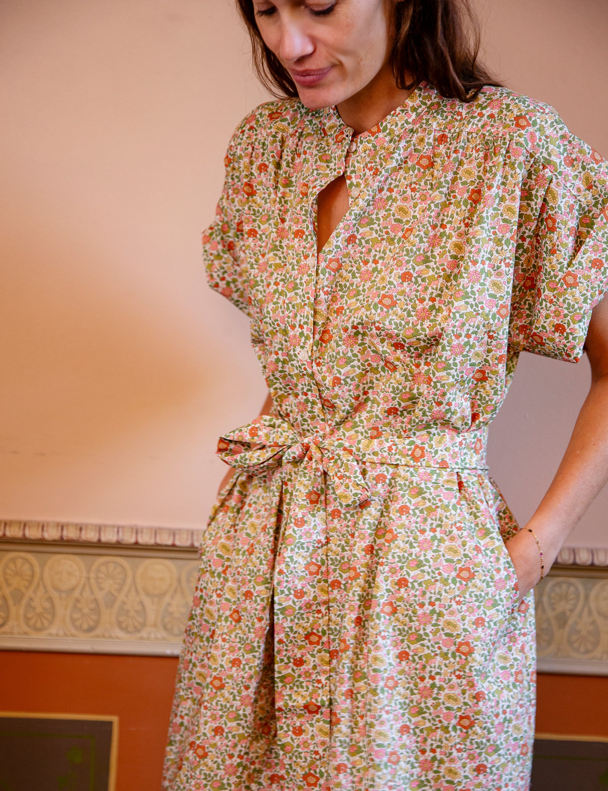 Woman wearing a floral dress with short sleeves and matching belt in an indoor setting