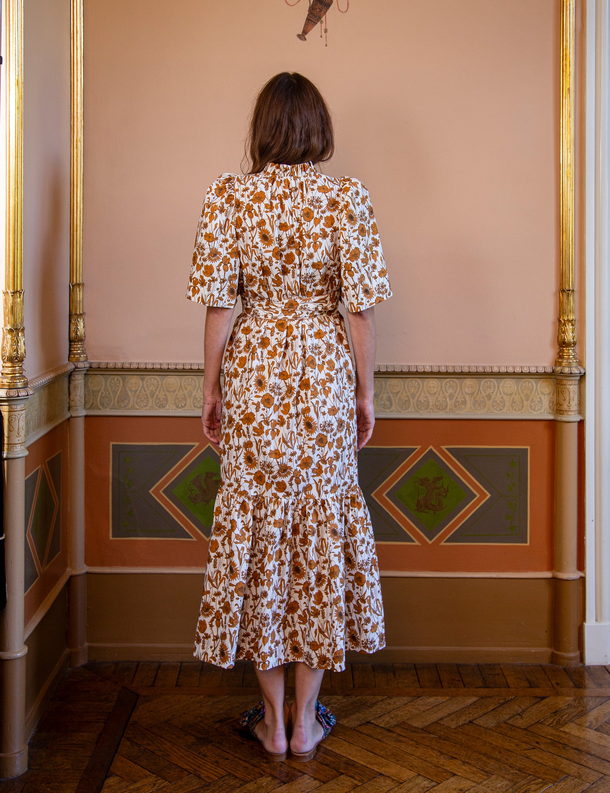 Woman wearing a white and brown floral summer dress with short puff sleeves and matching fabric belt