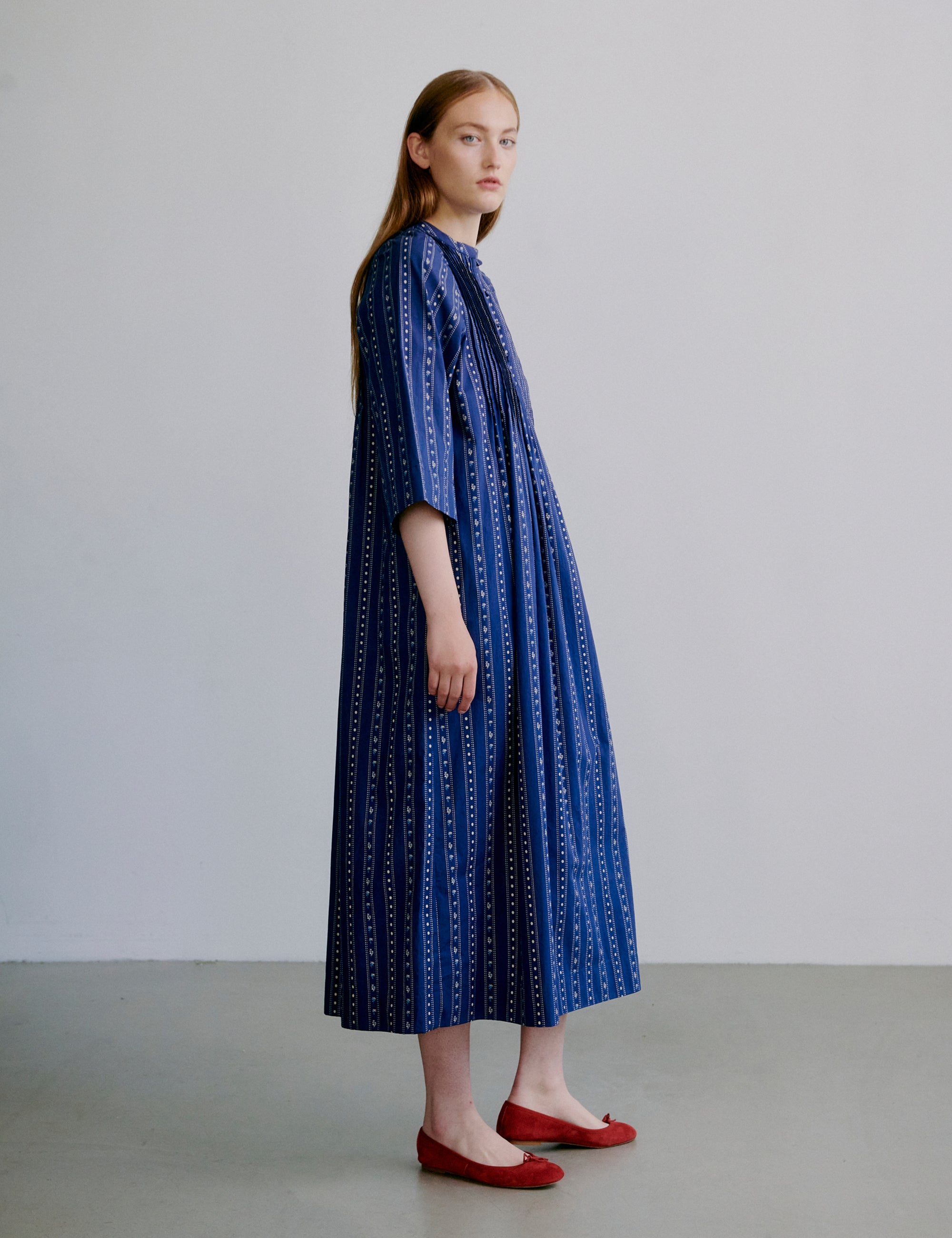 Woman wearing a blue stripe patterned dress with buttons and semi-long wide sleeves