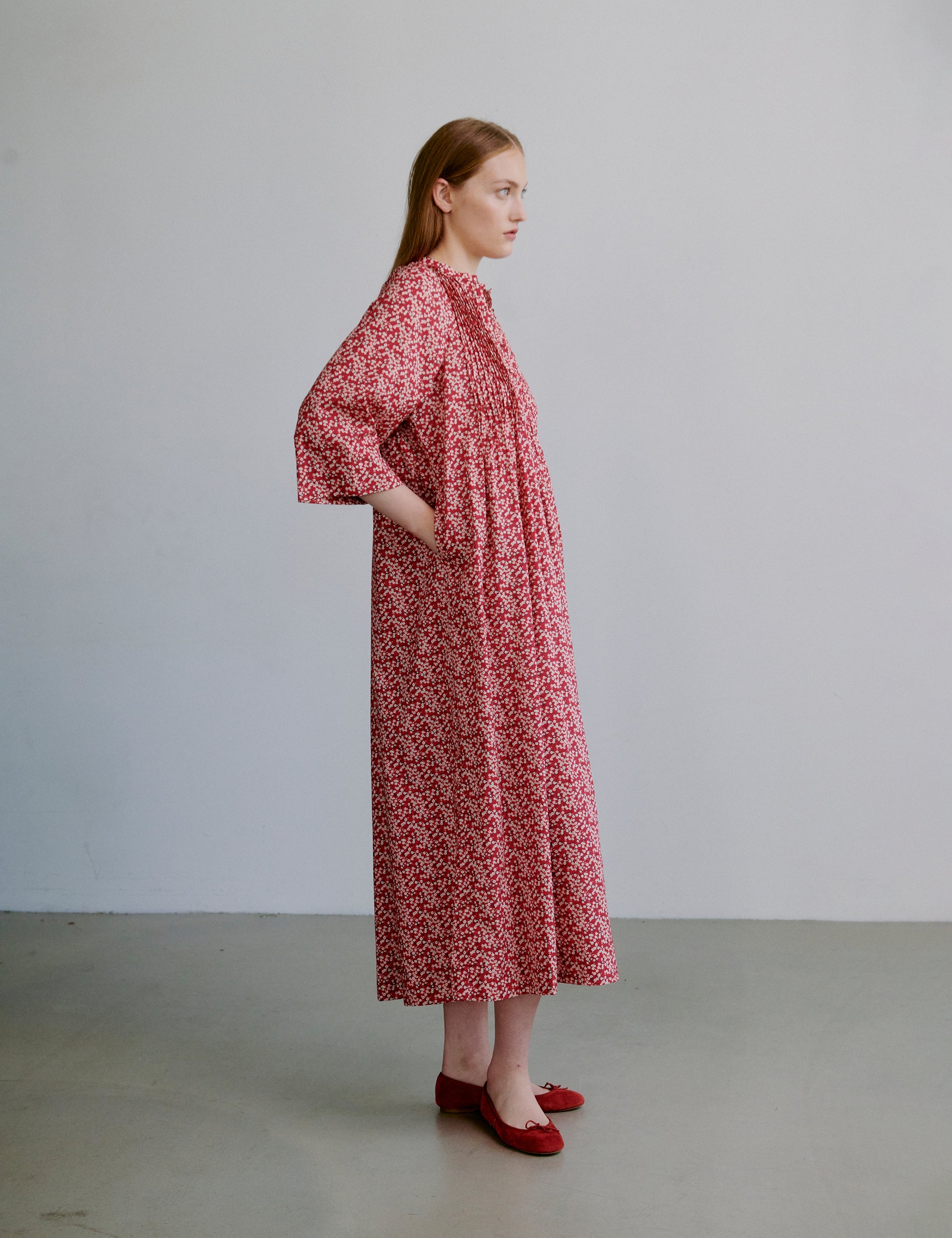 Woman wearing a red floral dress with buttons at the front and long sleeves
