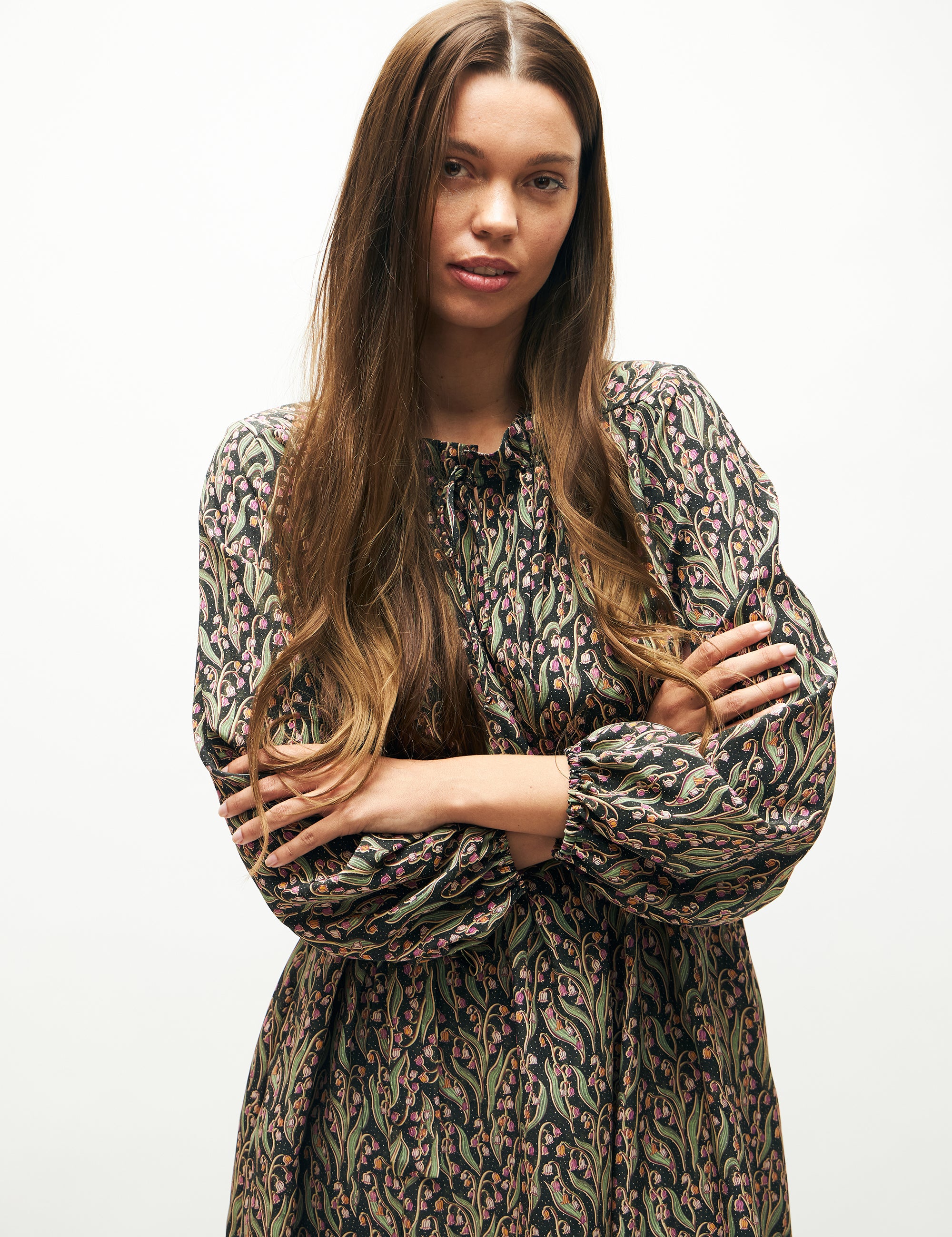 Woman in long sleeved dress with pink and green flower pattern and matching belt