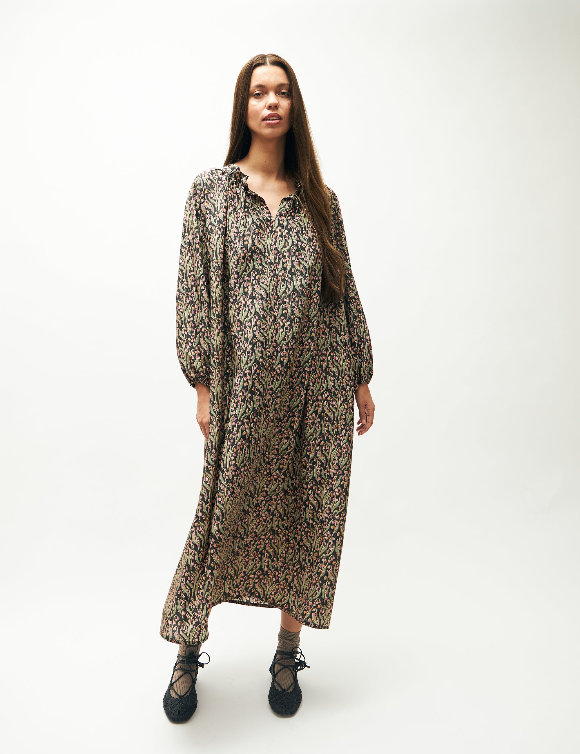Woman in relaxed long sleeved dress with pink and green flower pattern