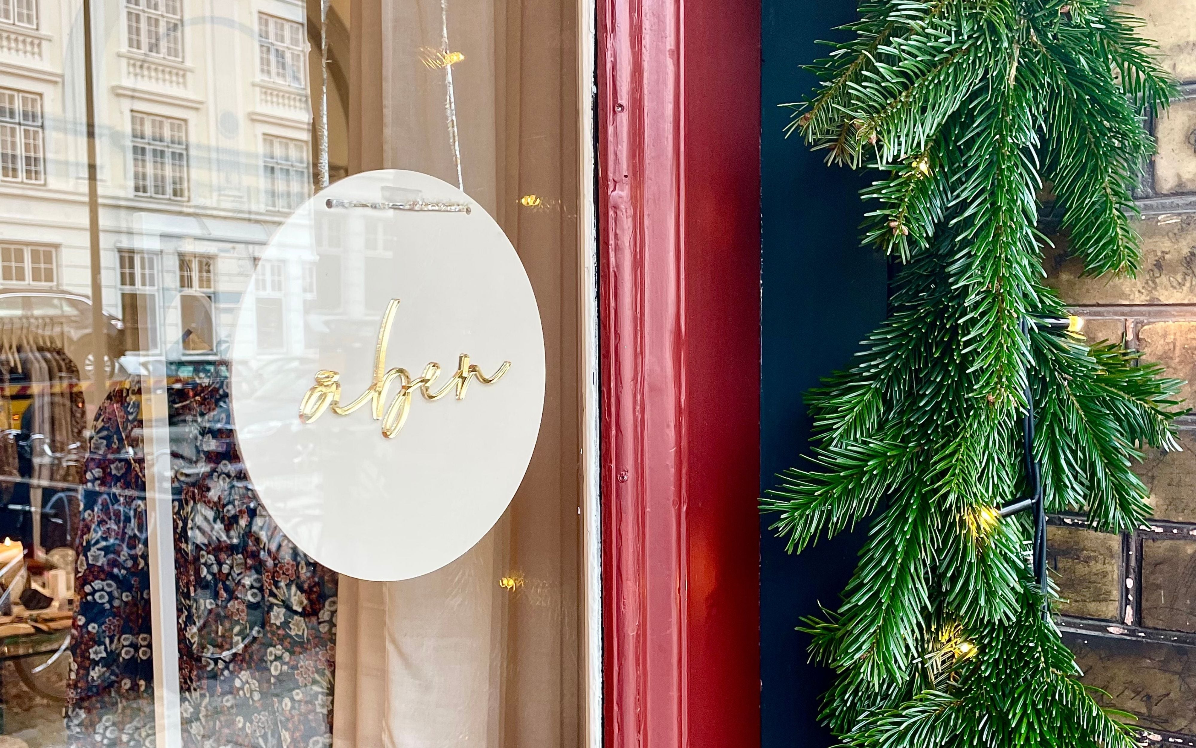 Decorative green garland with lights on a door next to a window with Christmas decorations.