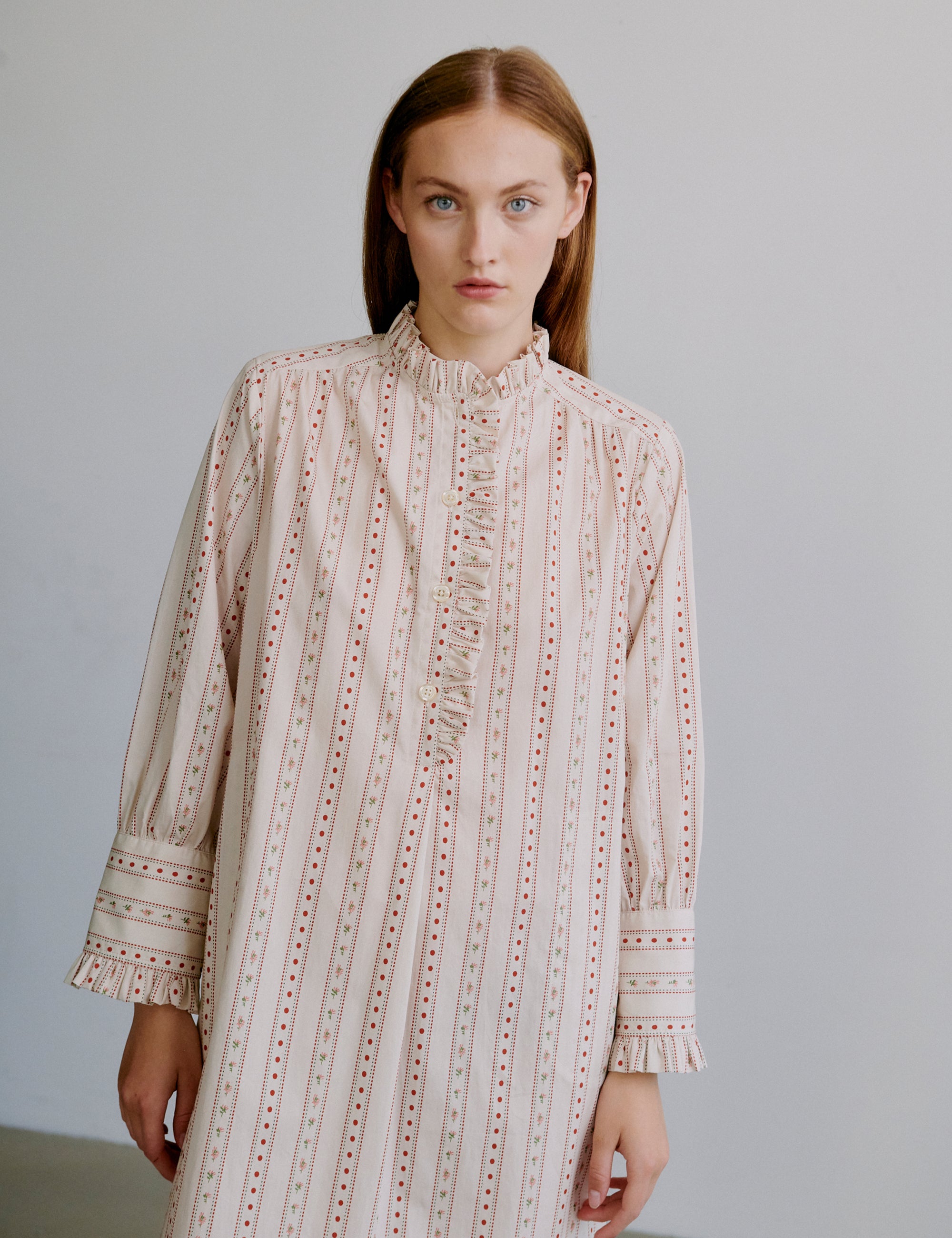 Woman wearing a beige patterned dress against a plain background