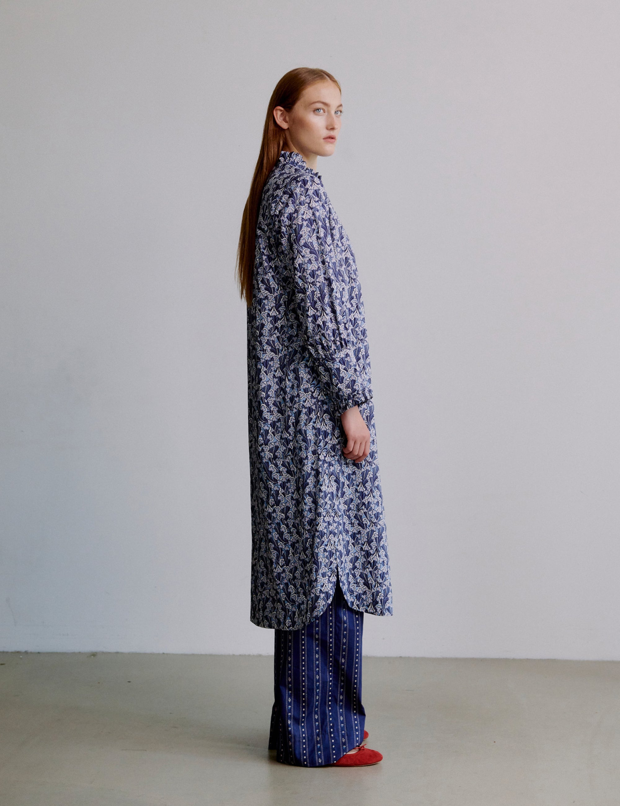 Woman wearing a long blue floral dress with blue striped pants