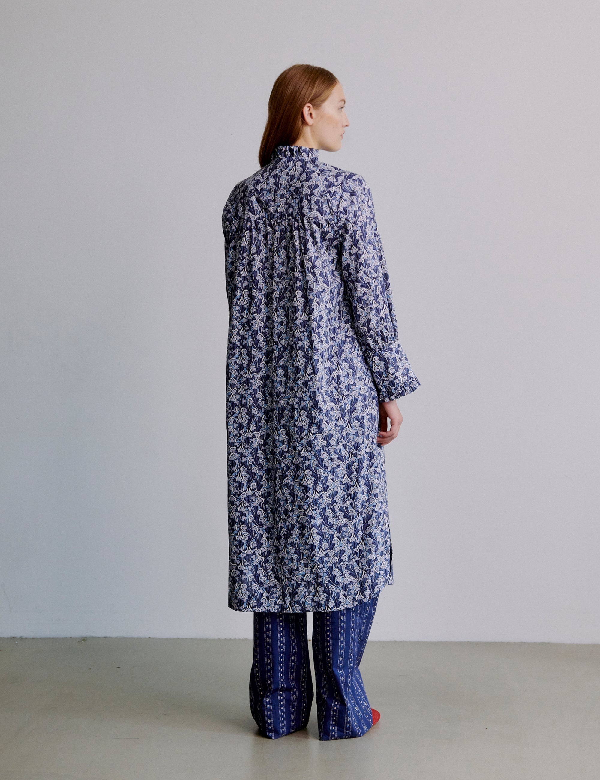 Woman wearing a long blue floral dress with blue striped pants