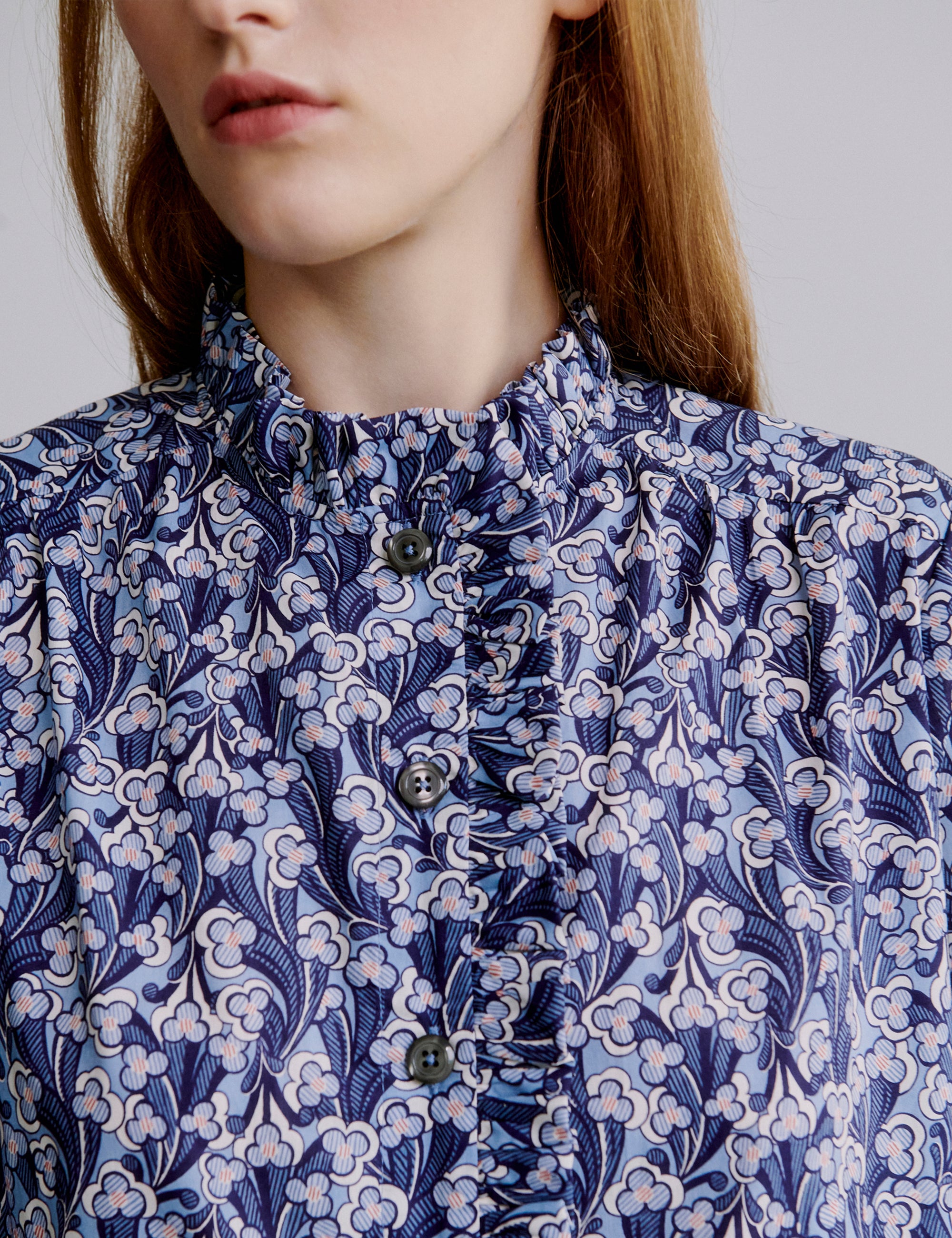 Close-up of woman wearing a blue and white floral patterned dress with buttons and frills