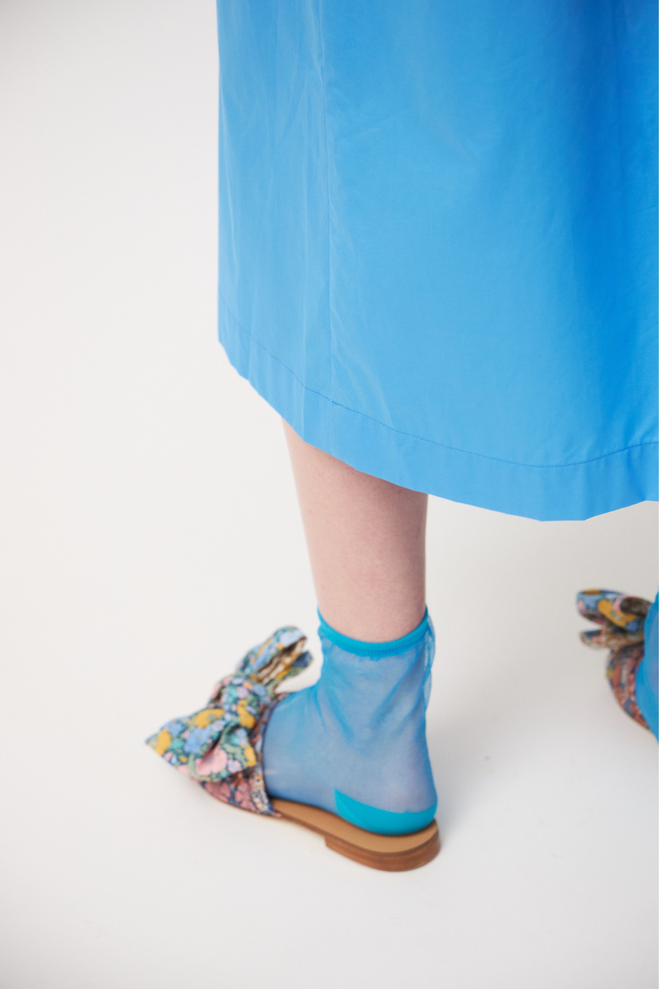 Woman in long blue cotton tunic dress and sandals with bows