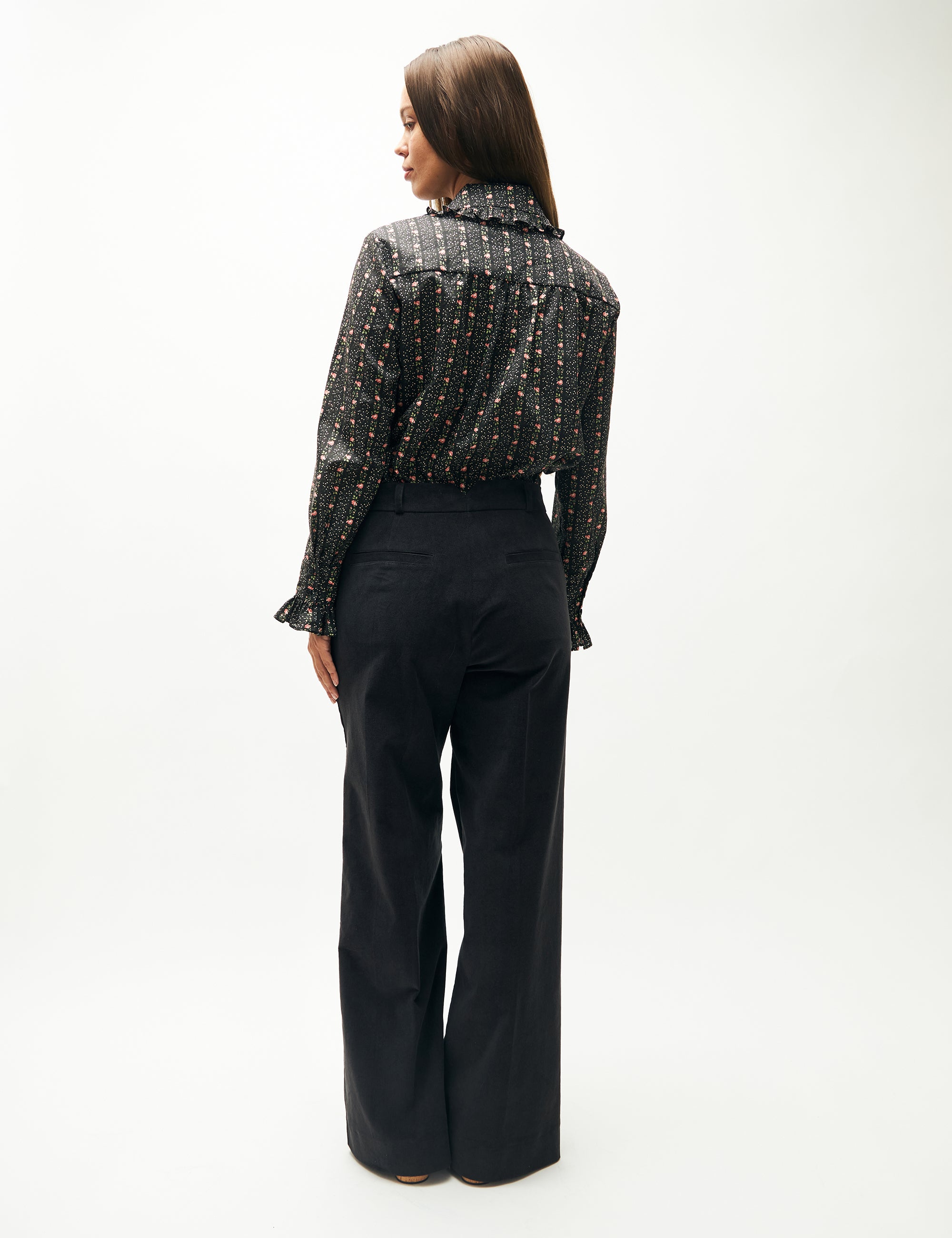Woman in wide blue velvet trousers and floral striped long sleeved blouse with collar