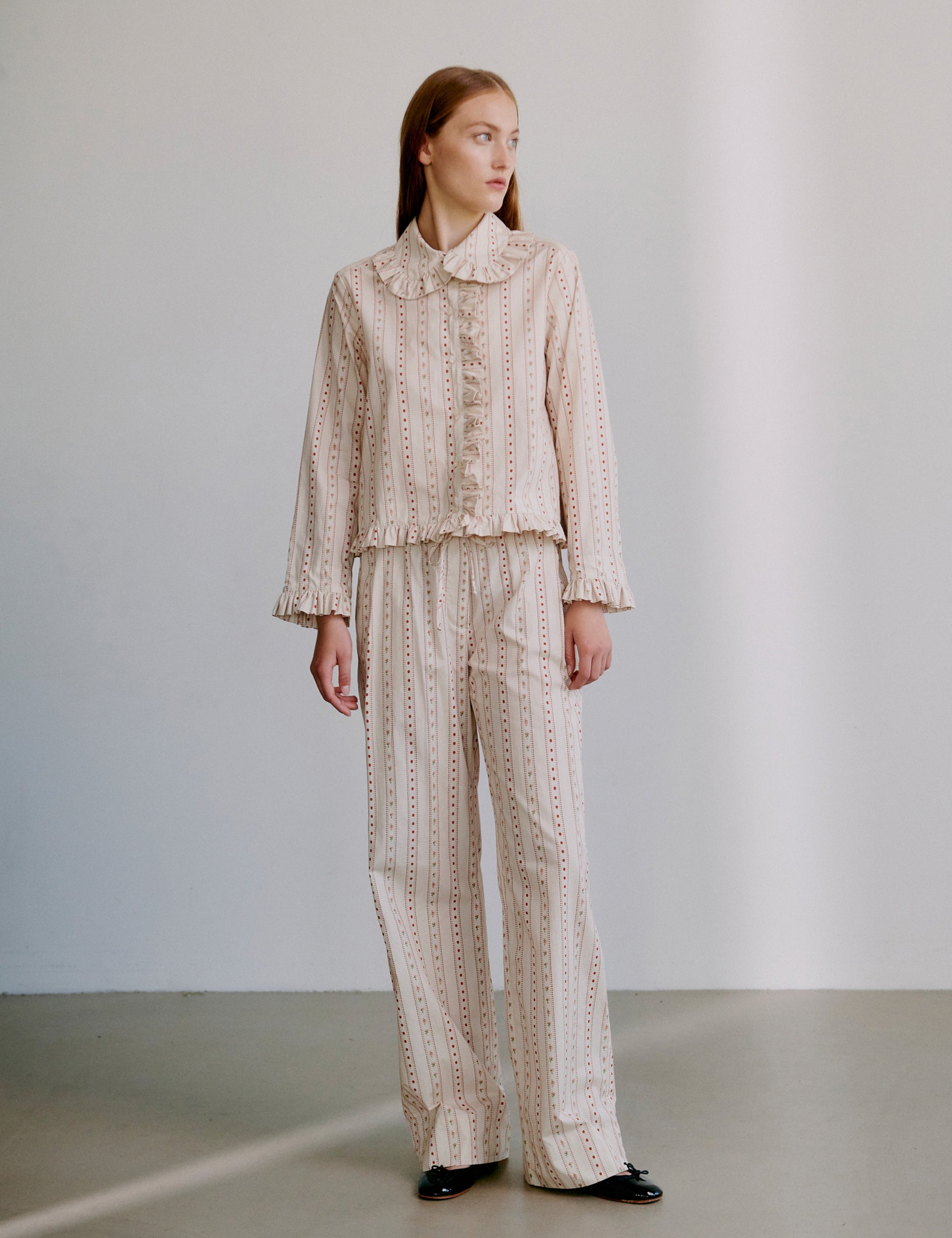 Woman wearing a matching shirt and pants set in creme and red pattern