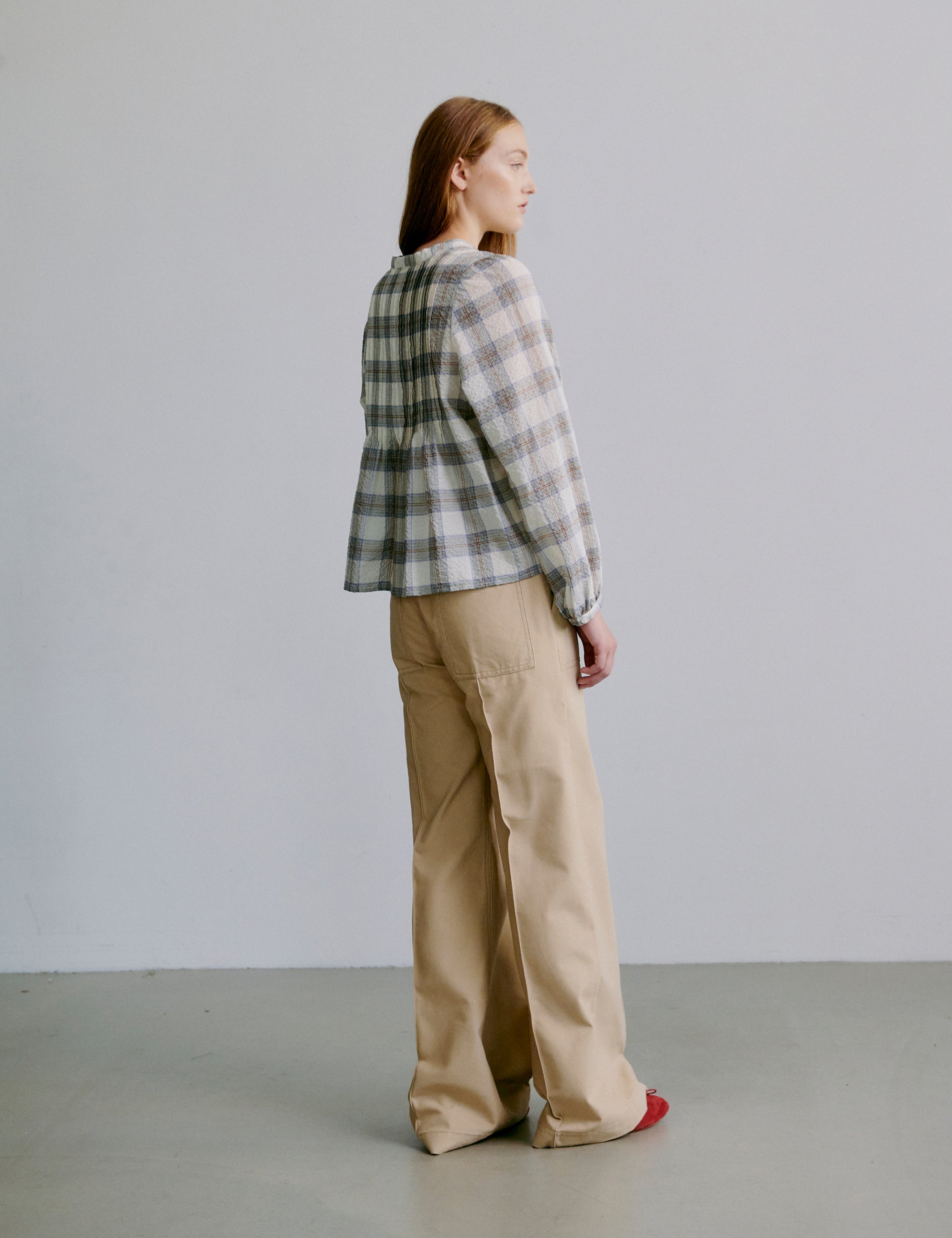 Woman wearing a check patterned grey and white shirt and beige pants