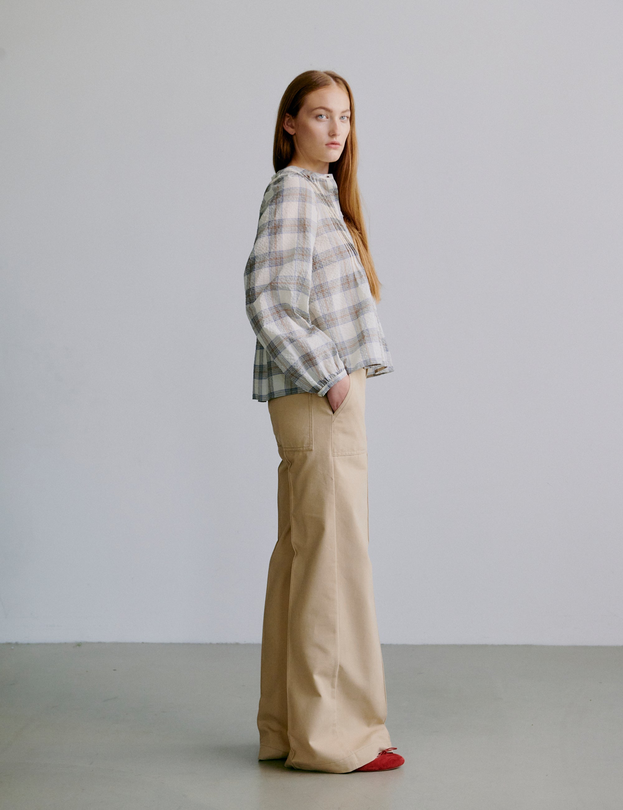 Woman wearing a check patterned grey and white shirt and beige pants