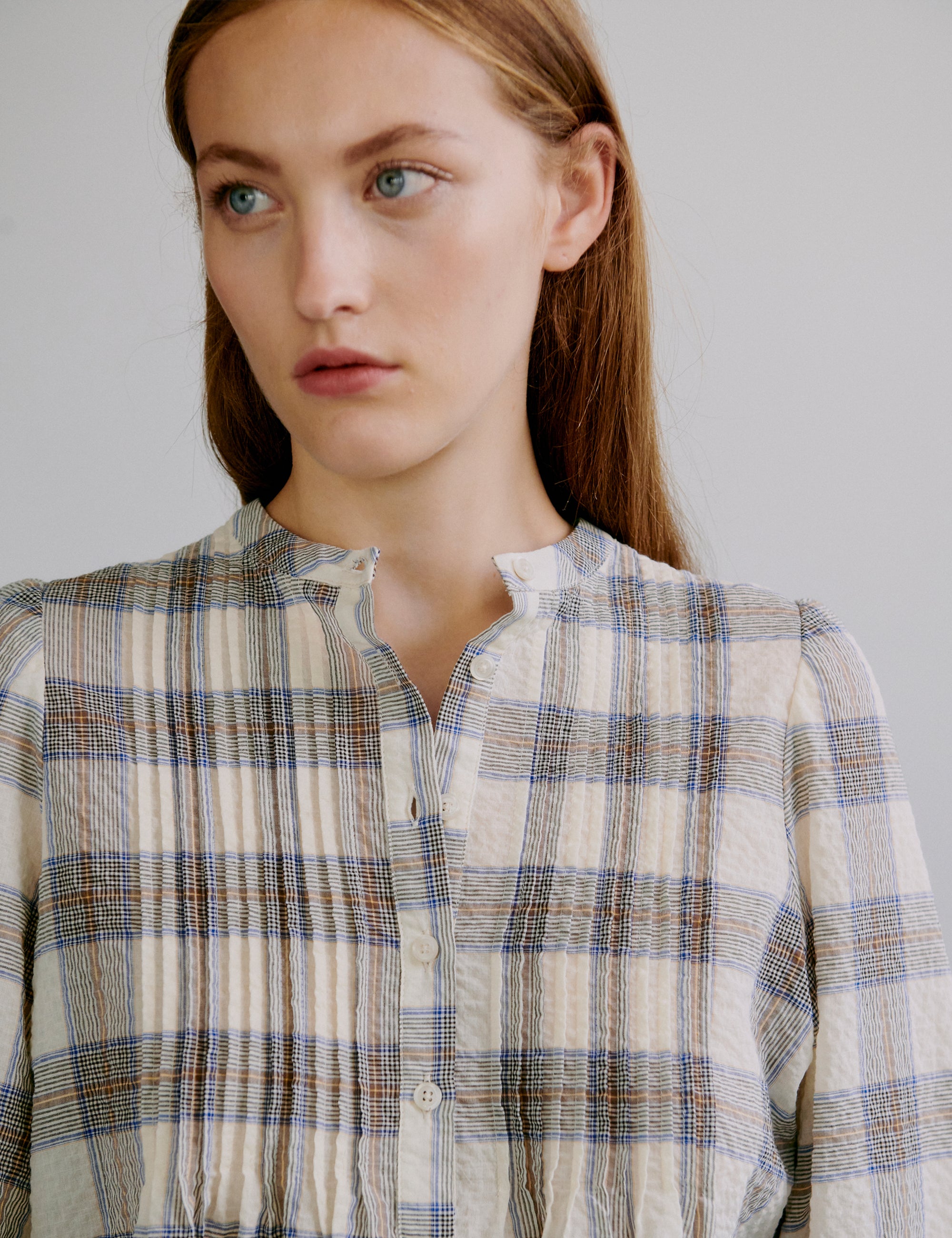 Woman wearing a check patterned seersucker shirt with front buttons