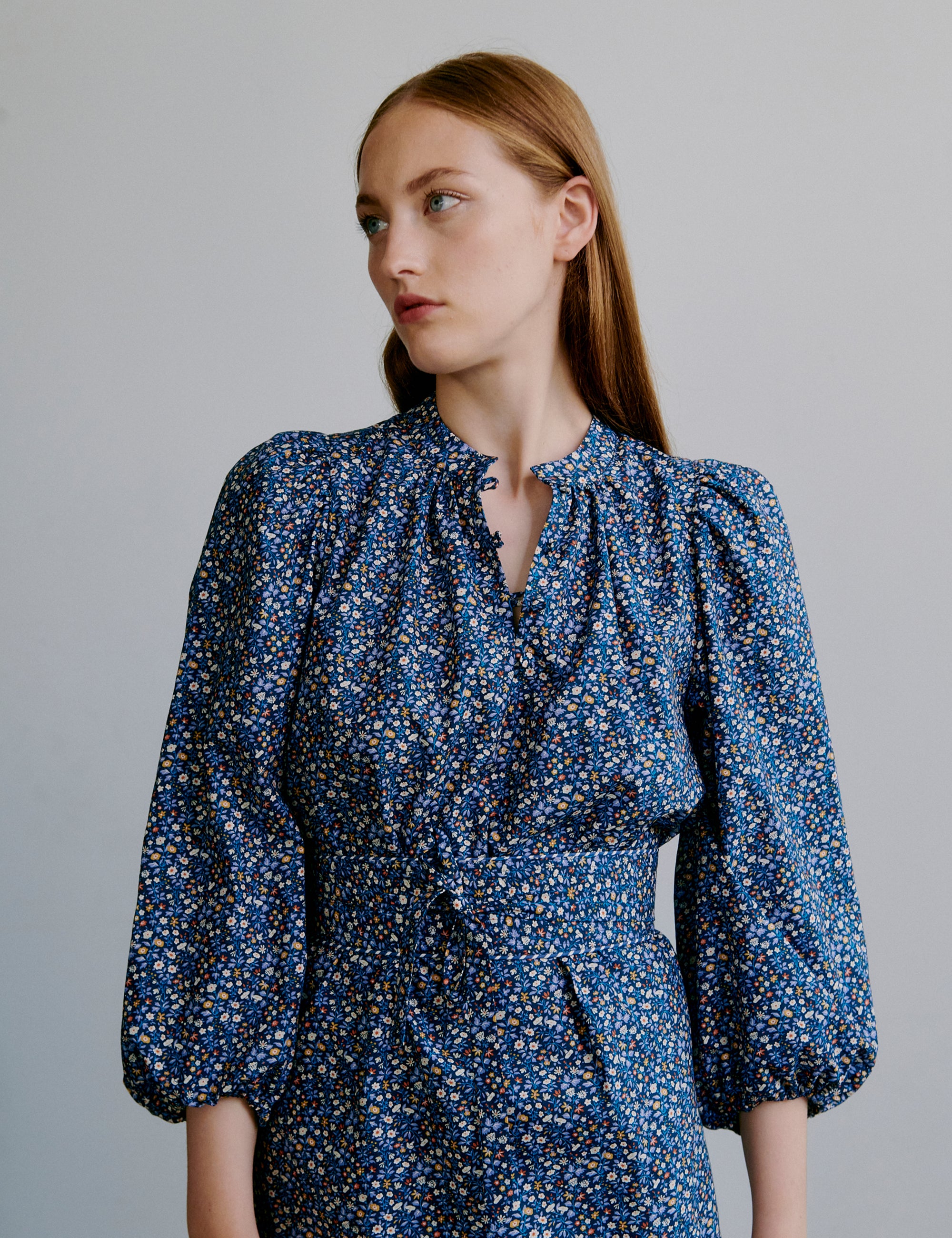 Woman wearing a short blue floral dress with puff sleeves and a matching belt