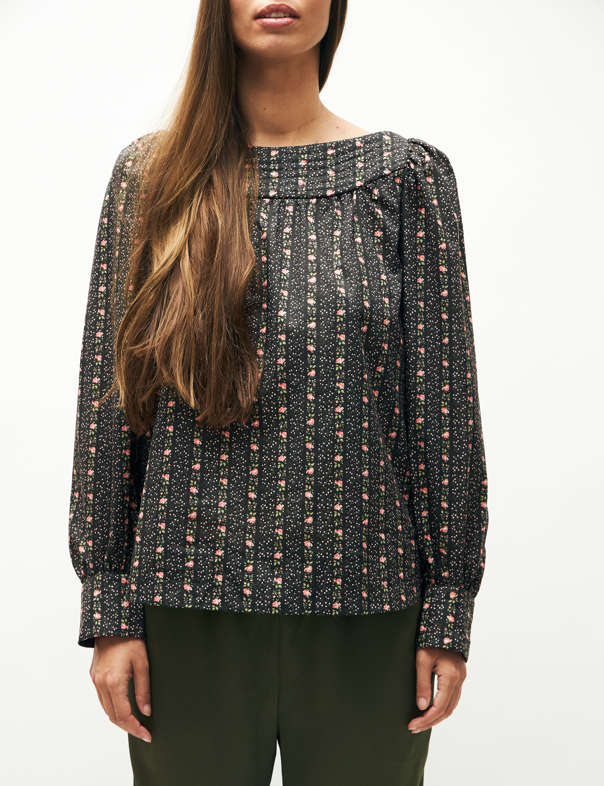 Woman in green pants and green flower patterned long-sleeved blouse