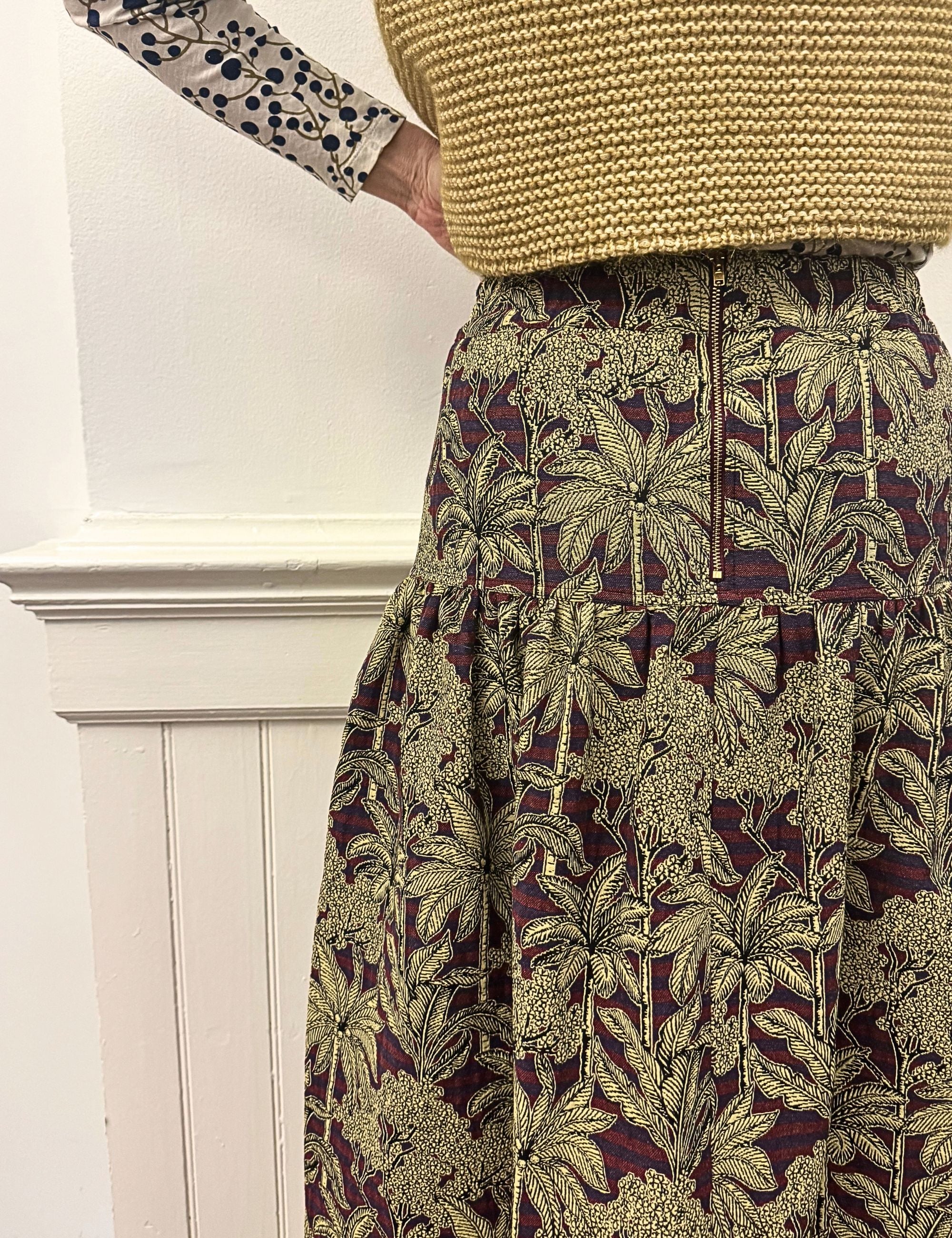 Woman in palm print skirt, blueberry print t-shirt and knitted wool vest