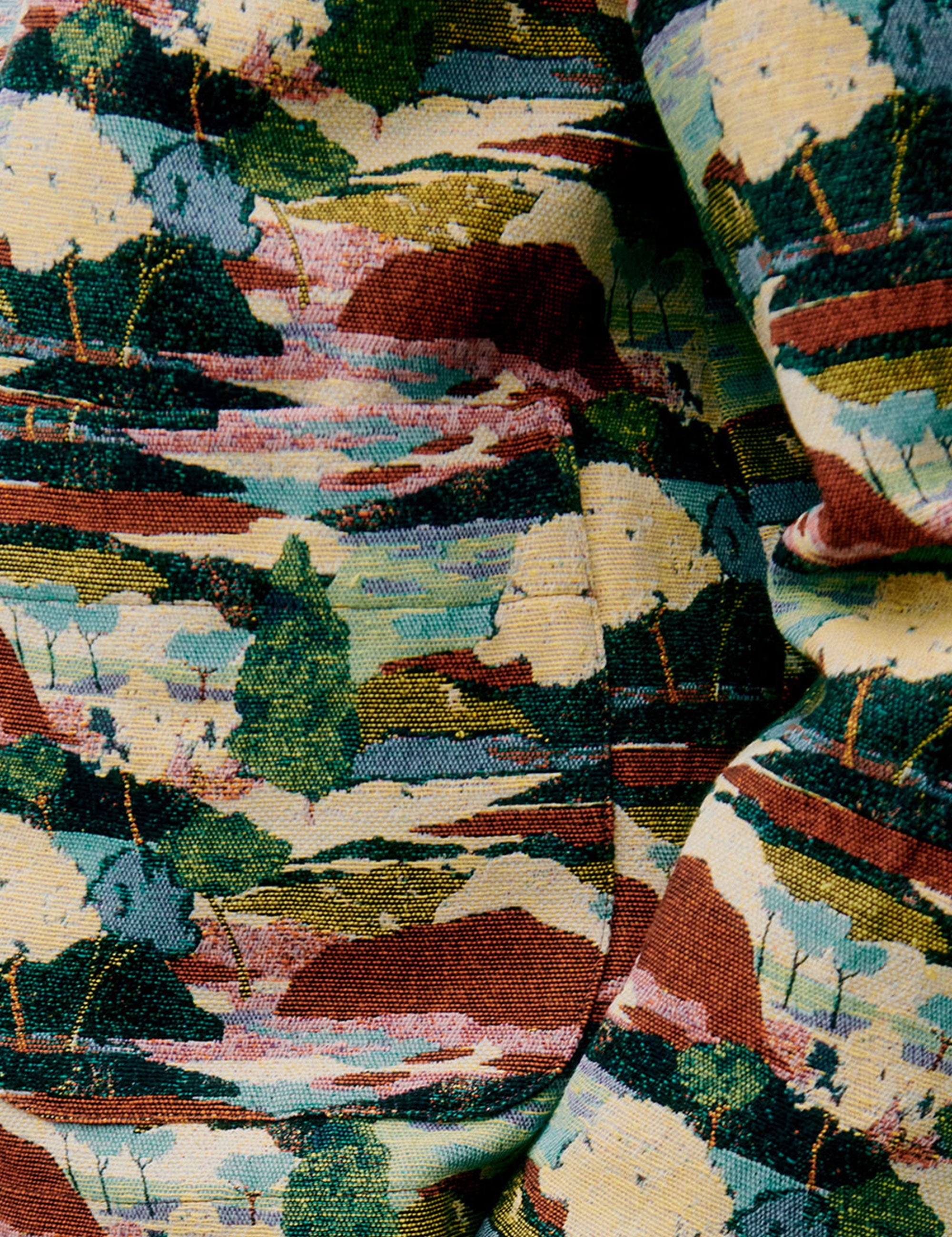 Closeup of jacquard fabric in earthy greens, reds and neutrals,