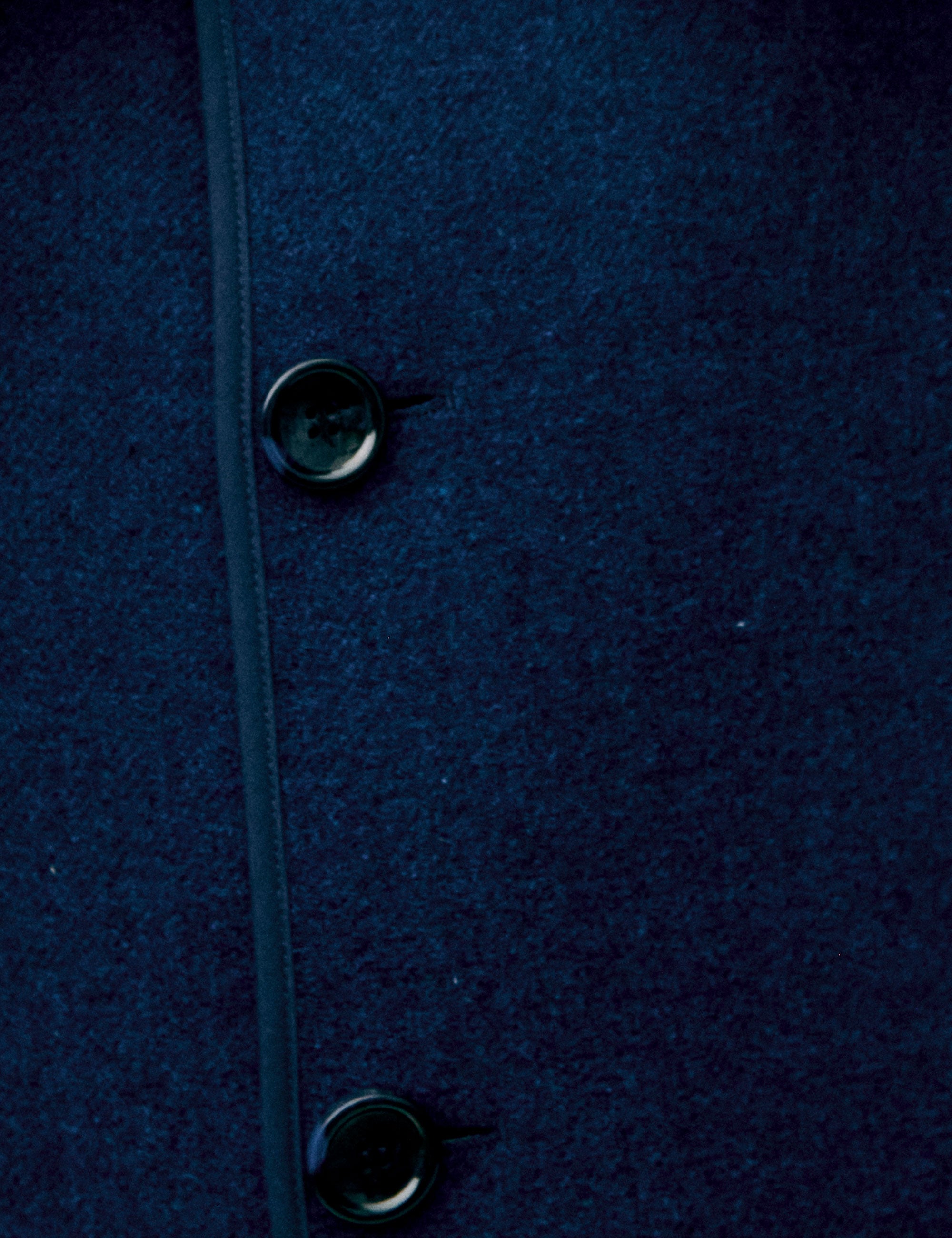 Close-up of a dark blue women's wool vest with a button detail