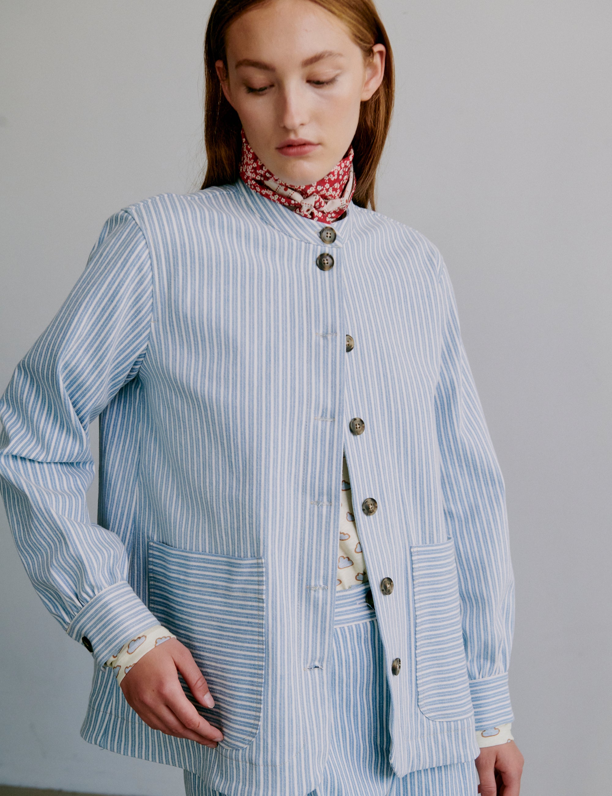 Woman wearing a light blue striped shirt jacket with buttons and pockets