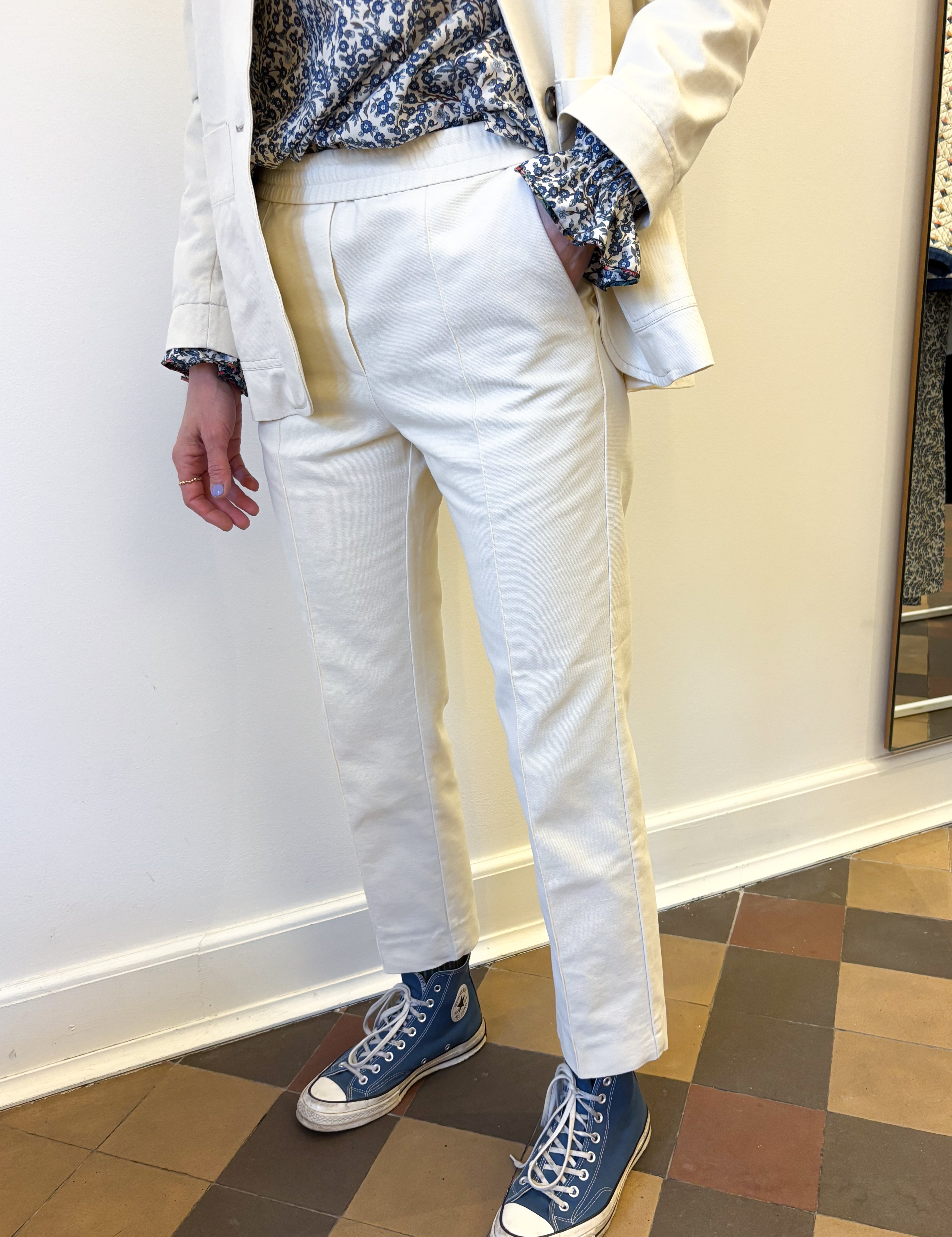 Woman in creme colored straight canvas pants, floral print shirt and creme colored blue jacket